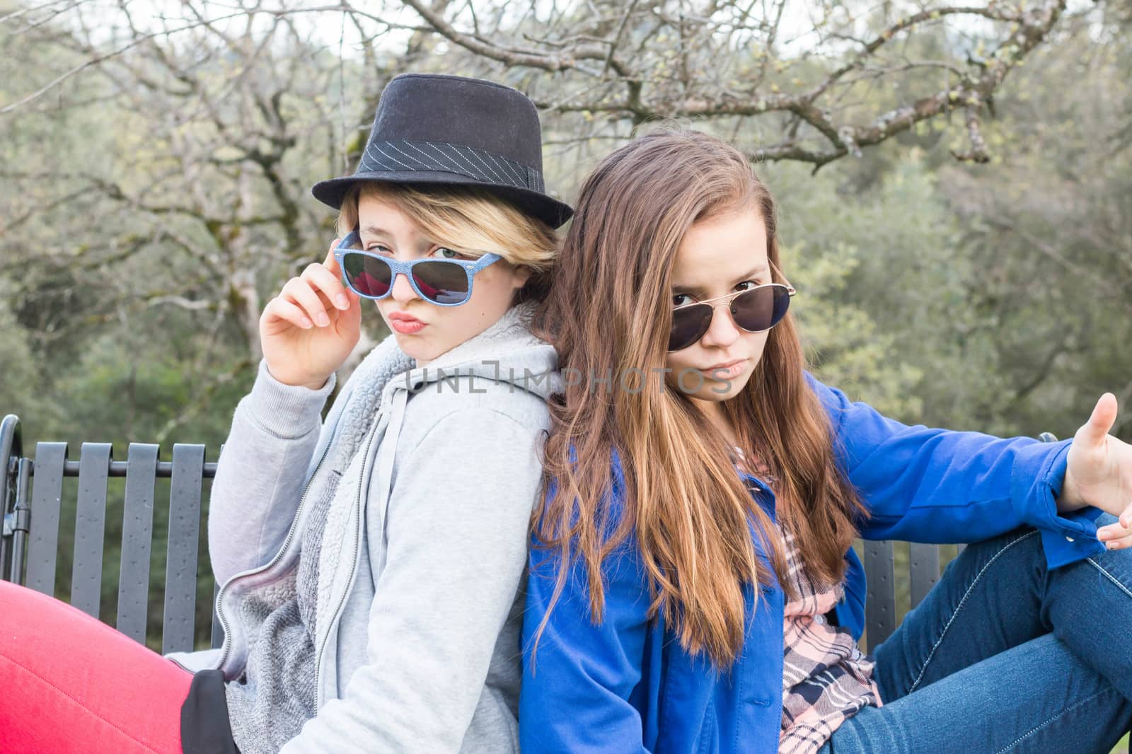 Two Girls Sitting on a Bench with Sunglasses