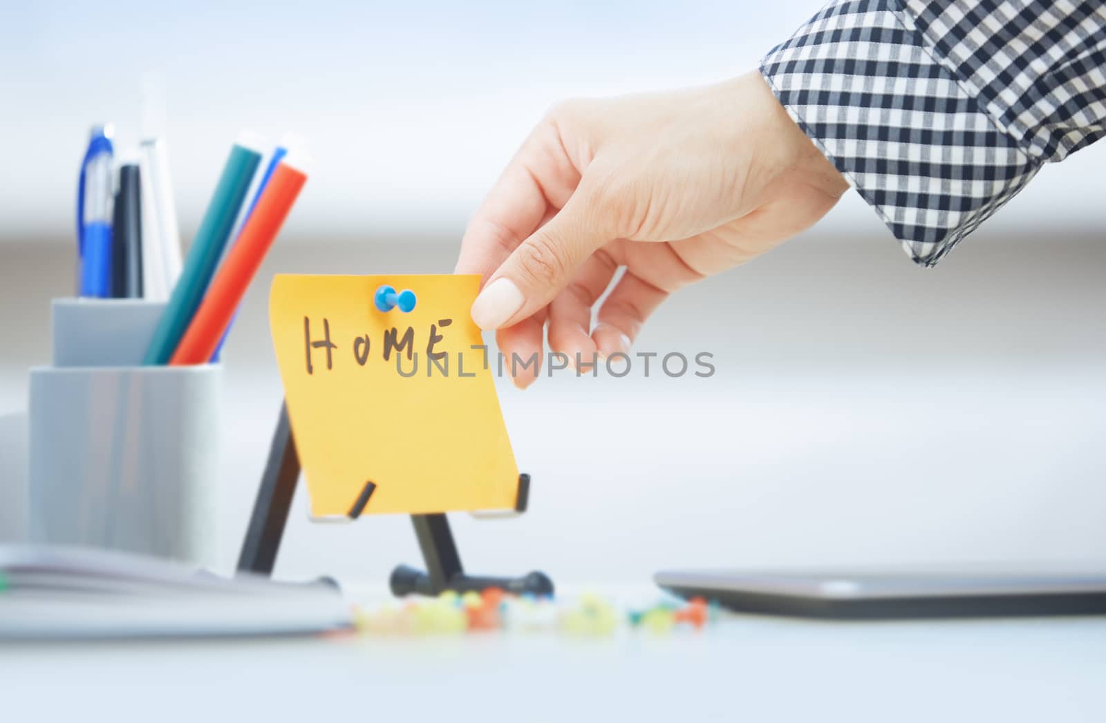 Human hand holding adhesive note with Home text