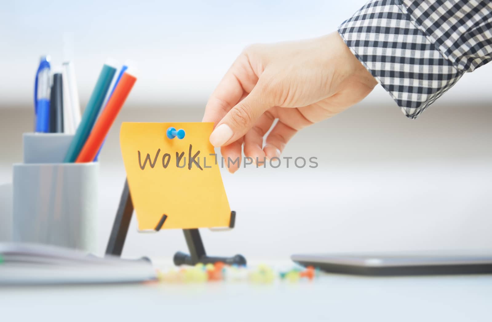 Human hand holding adhesive note with Work text