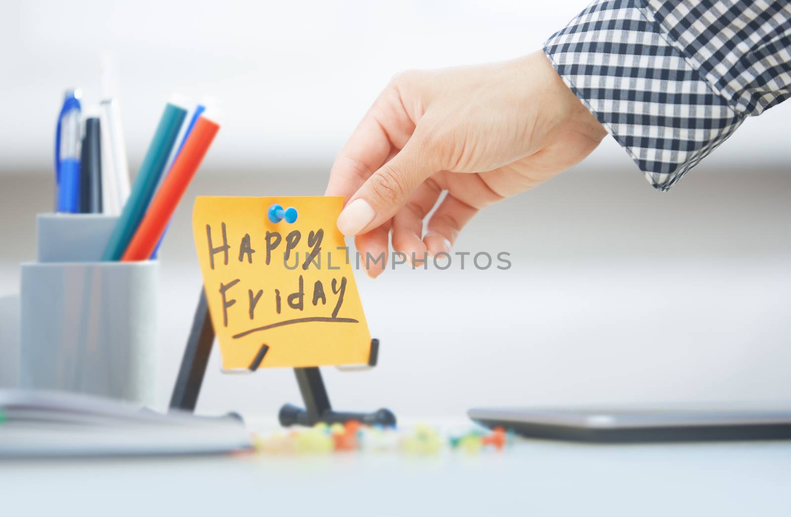 Human hand holding adhesive note with Happy Friday text