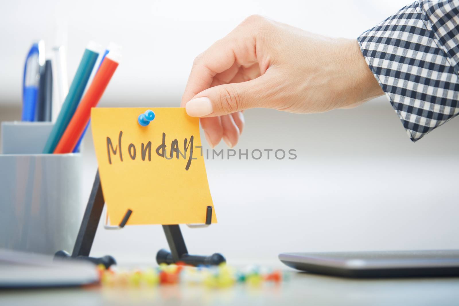 Human hand holding adhesive note with Monday text