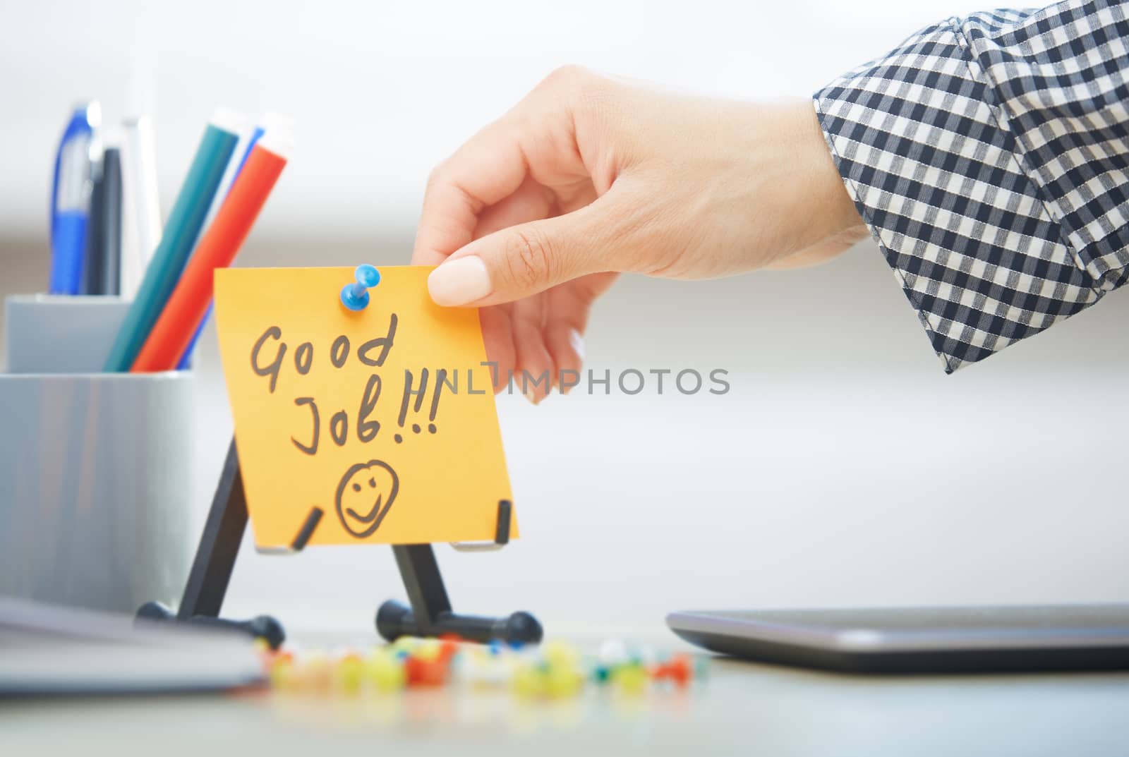 Human hand holding adhesive note with Good Job text