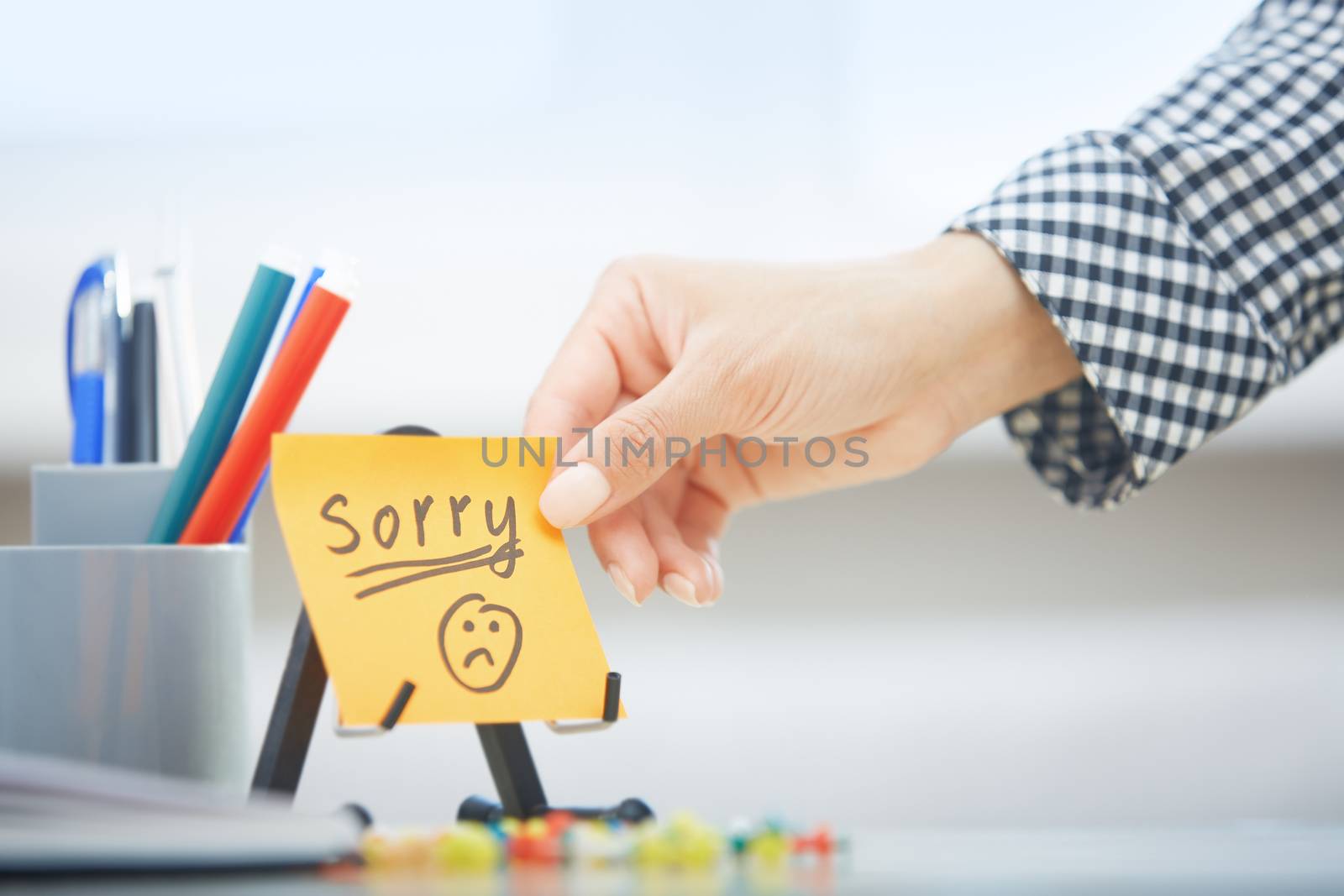 Human hand holding adhesive note with Sorry text