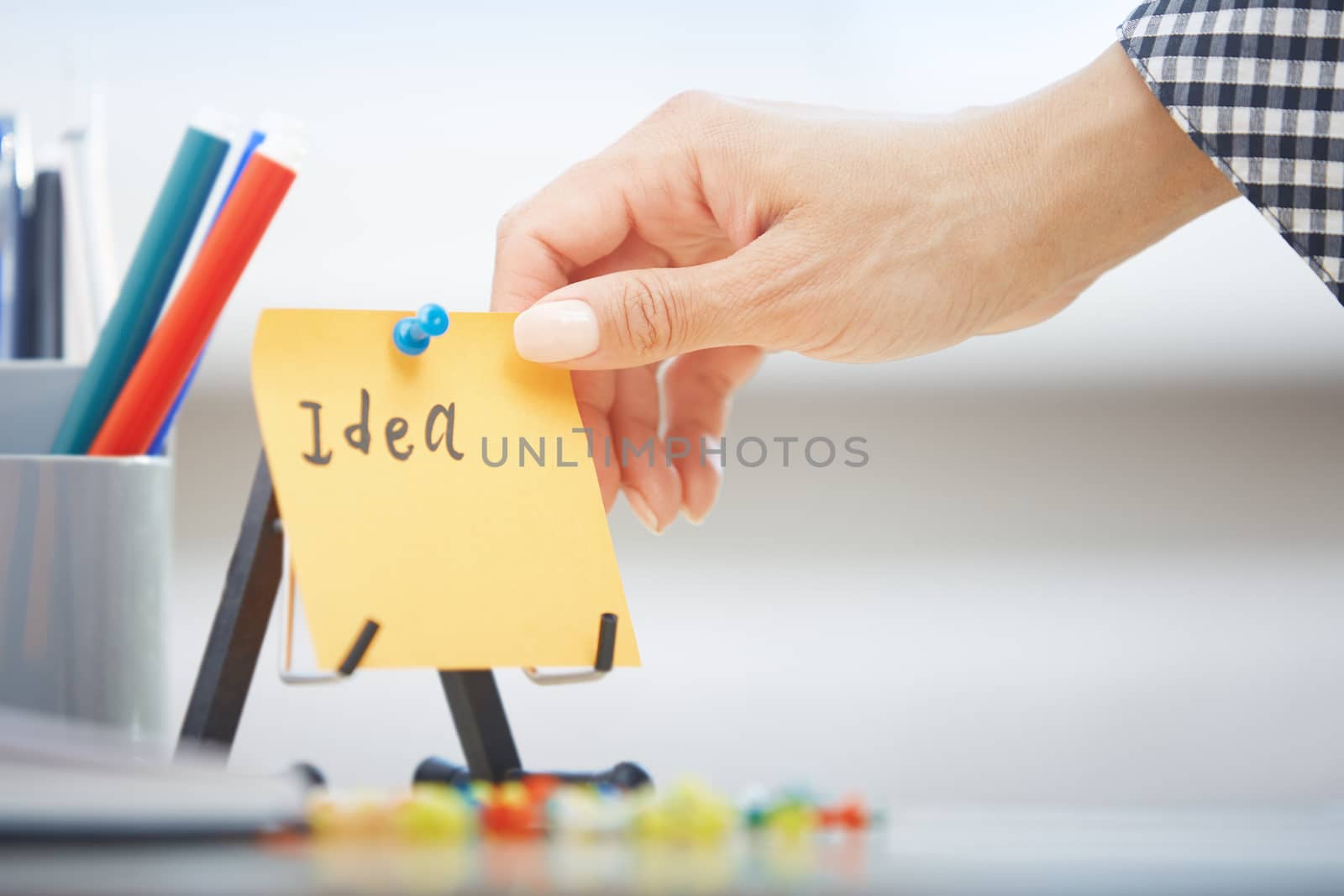 Human hand holding adhesive note with Idea text