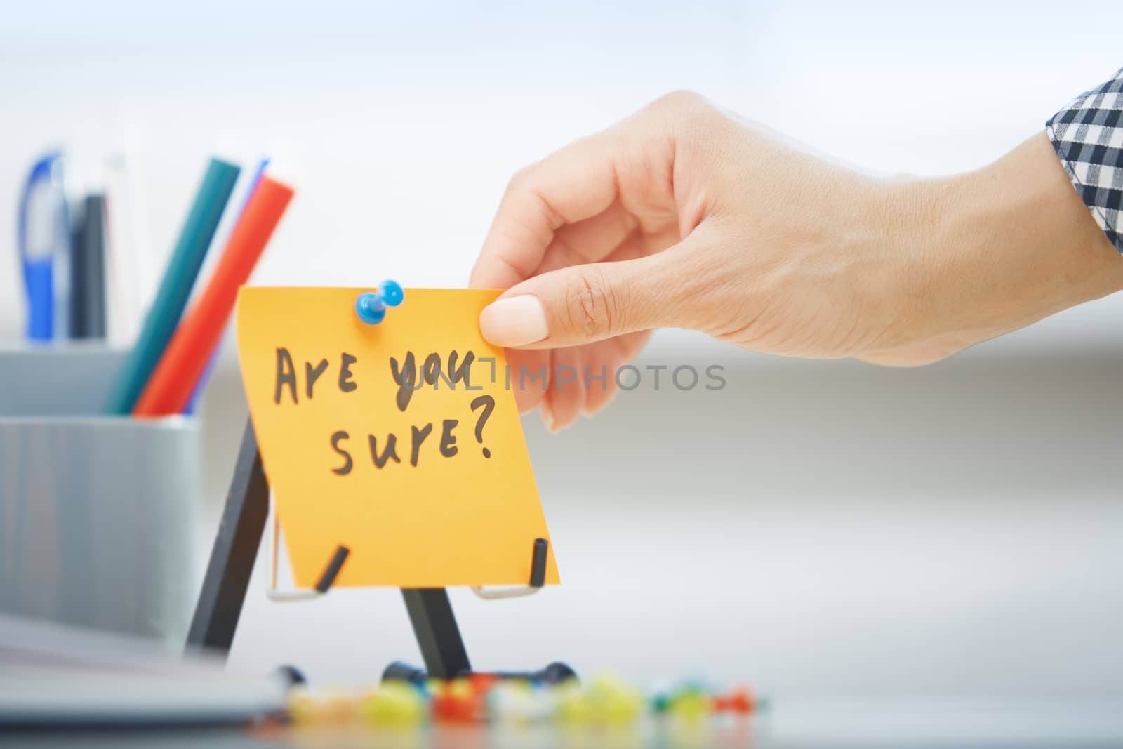 Human hand holding adhesive note with Are you sure text