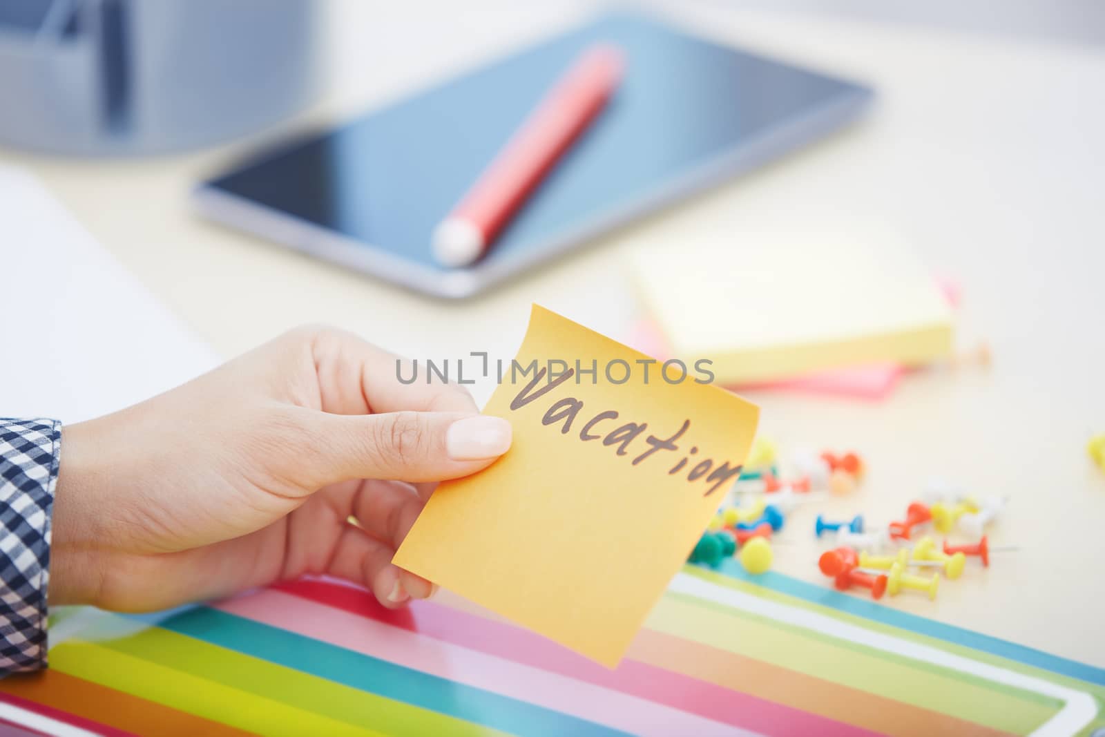 Human hand holding adhesive note with Vacation text