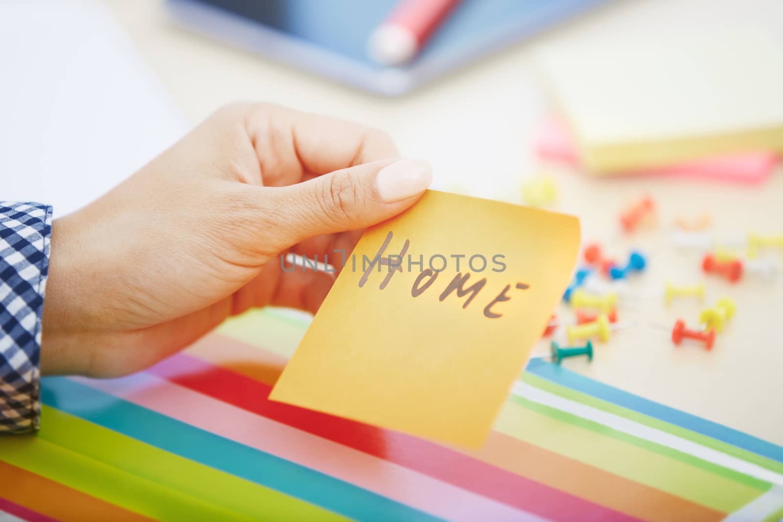 Human hand holding adhesive note with Home text