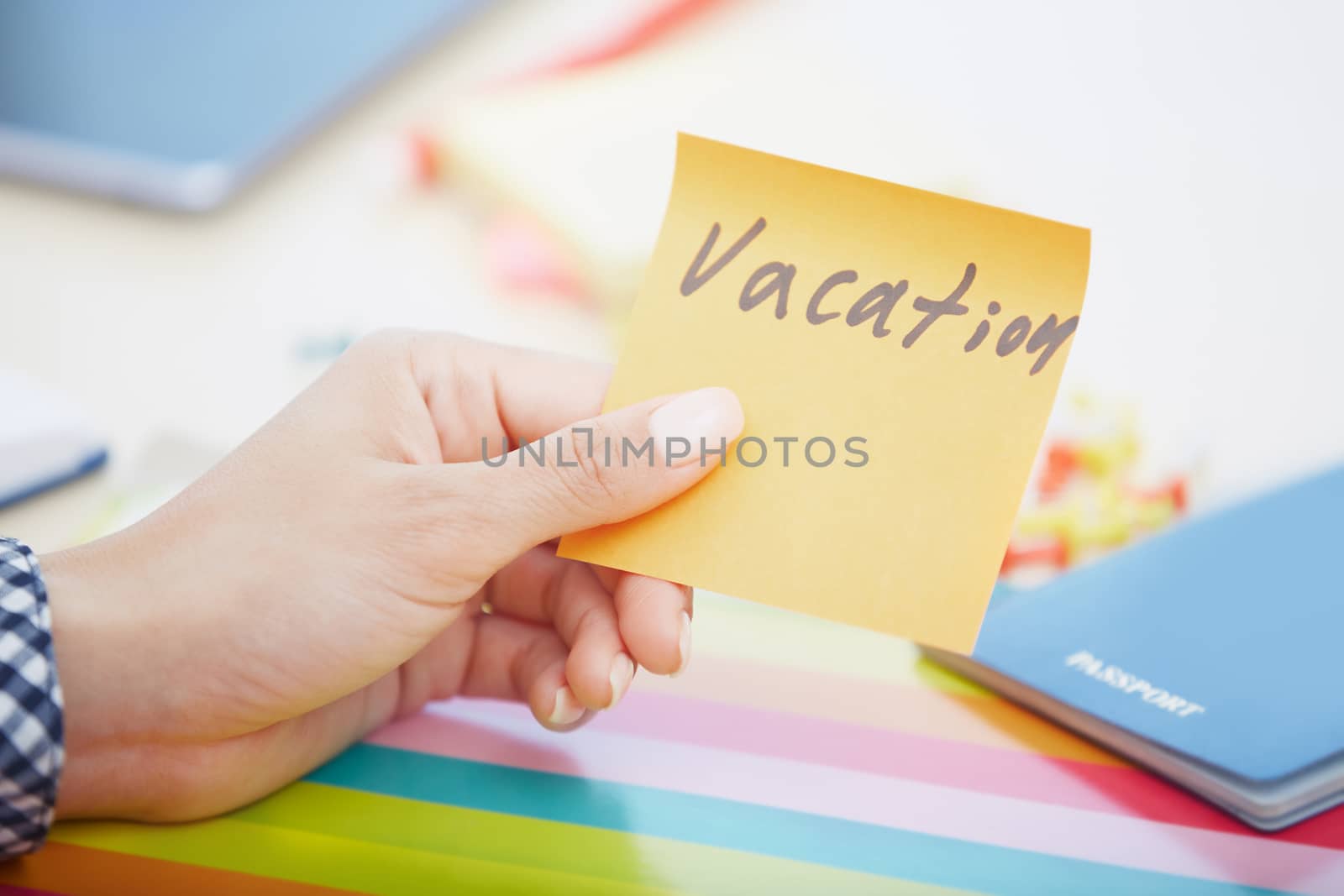 Human hand holding adhesive note with Vacation text