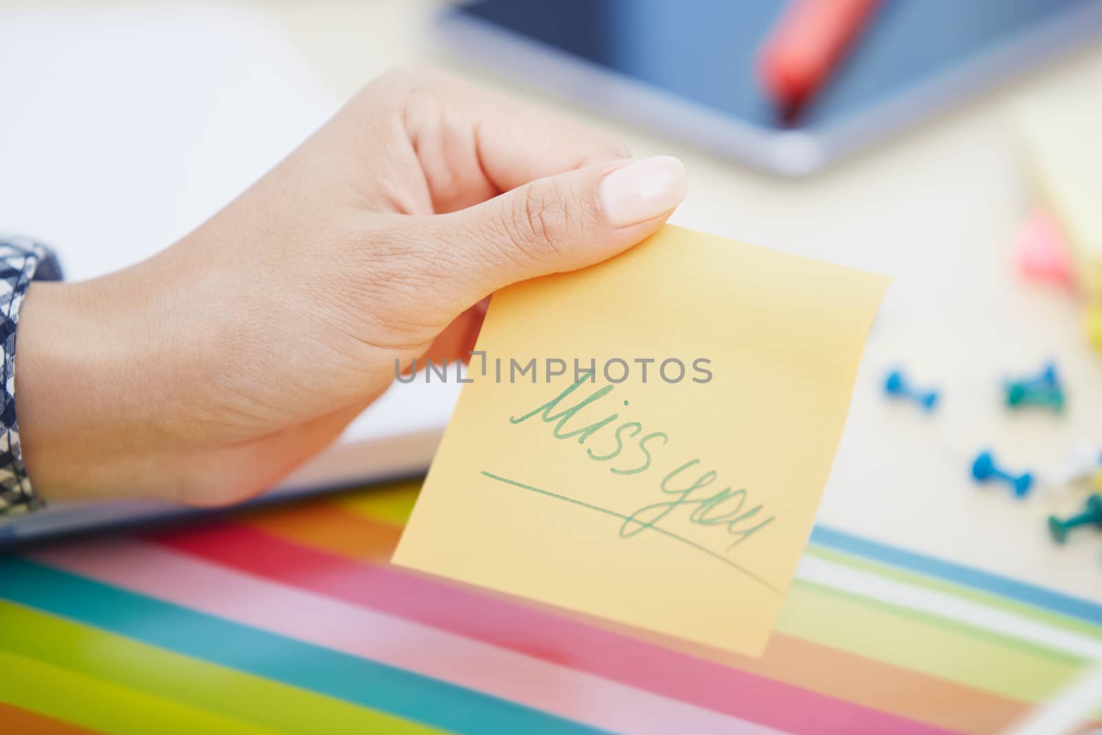 Human hand holding adhesive note with Miss you text