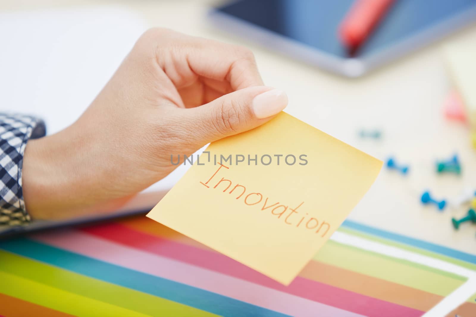 Human hand holding adhesive note with Innovation text