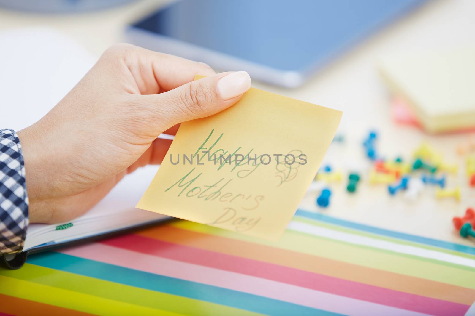 Human hand holding adhesive note with Happy mothers day text