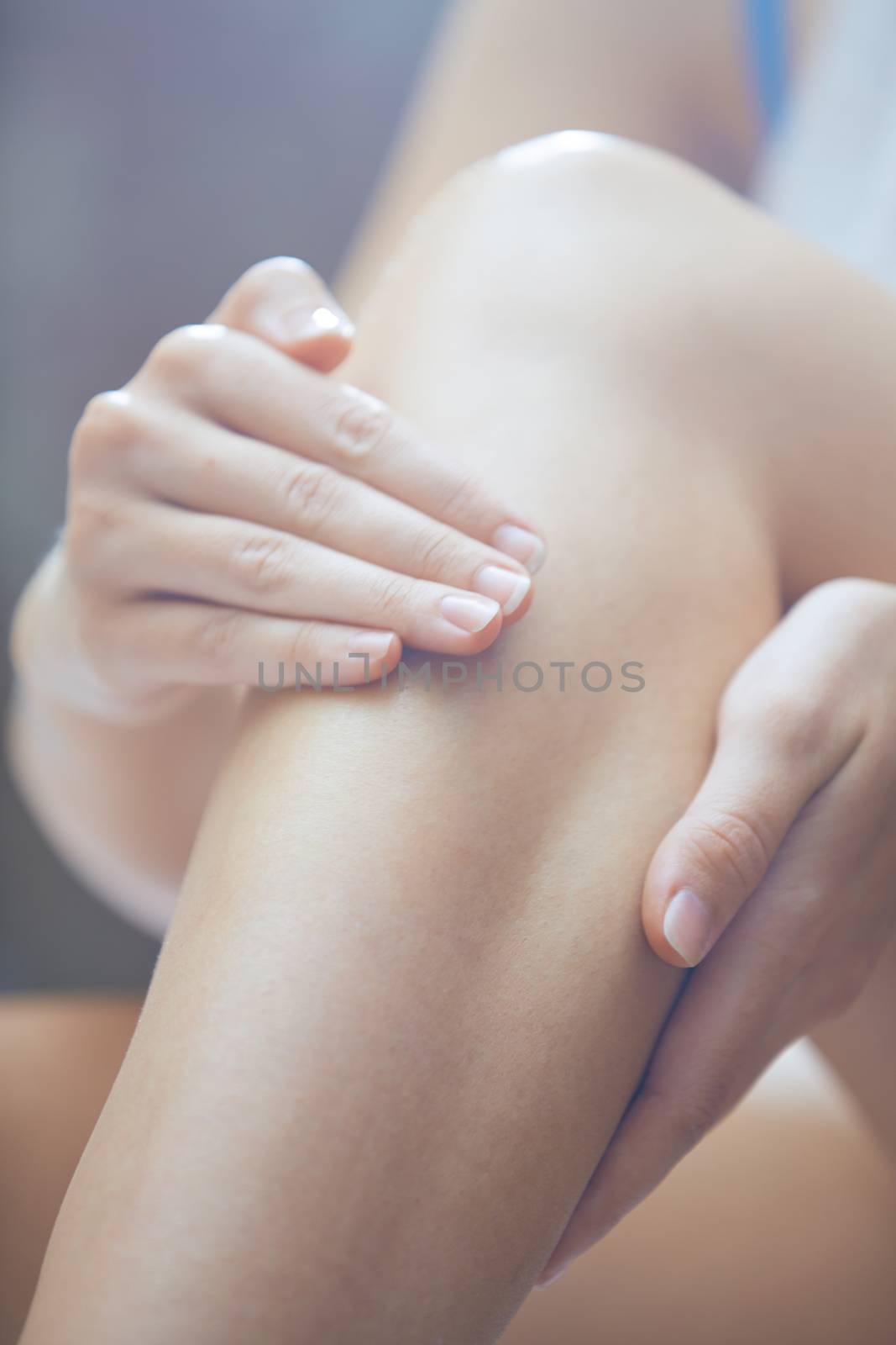 Woman doing leg massage and applying moisturizing cream