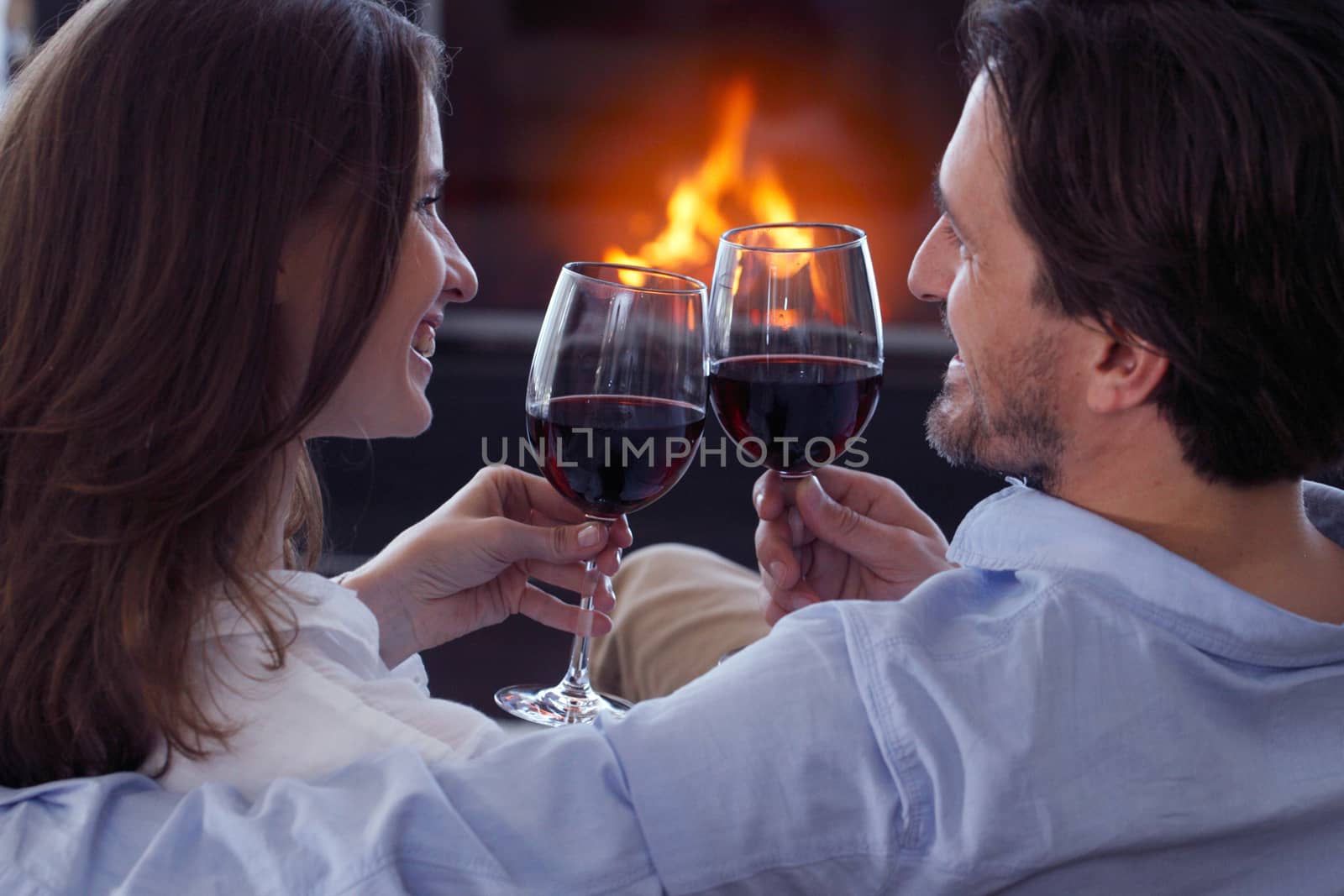 Romantic couple drinking wine at home near fireplace