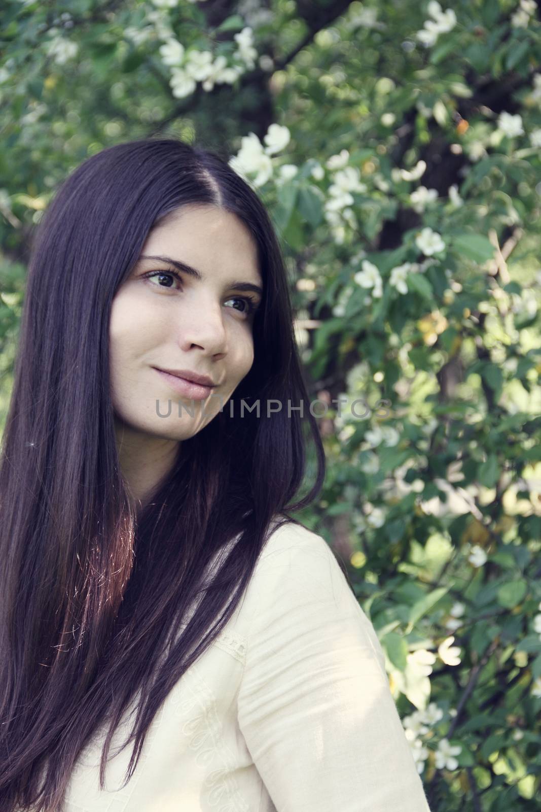 Portrait od a beautiful young woman near spring apple flowers