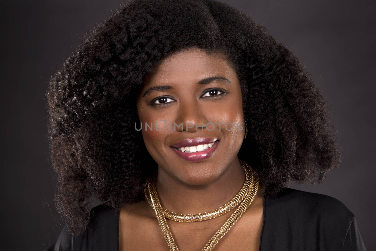 beautiful young black woman is wearing dark dress on grey background