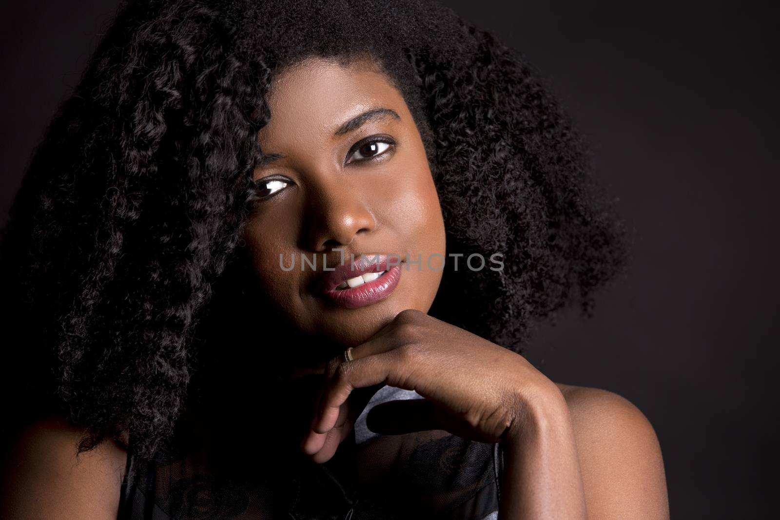 beautiful young black woman is wearing dark dress on grey background