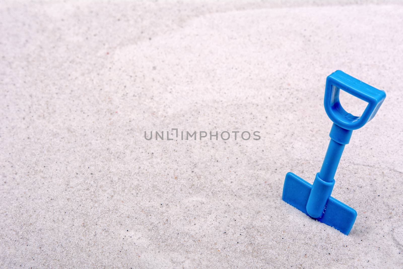 Blue scoop on a grey sand background