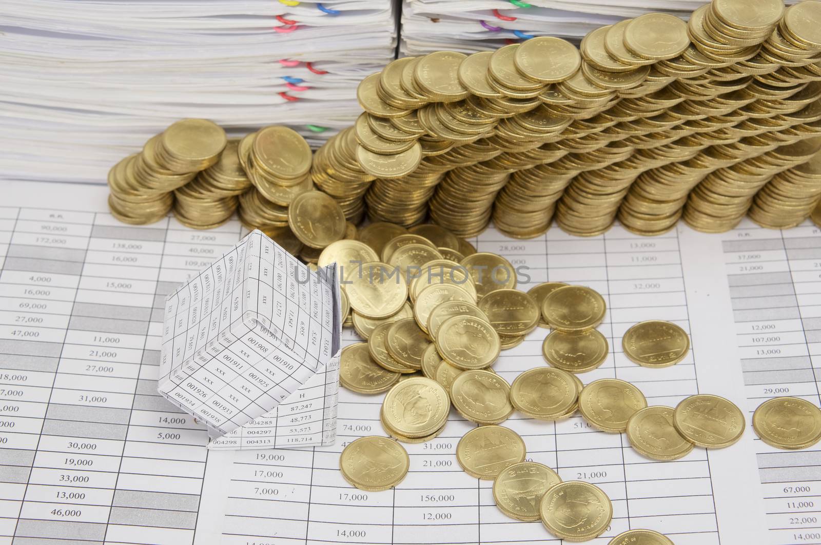 Close up bankruptcy of house on finance account have step pile of gold coins collapse and pile of paperwork as background.