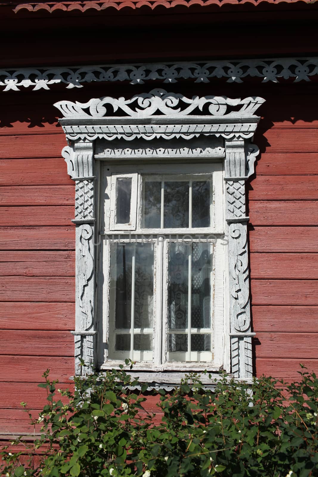 Window decorated with wood carvings on  log wall farmhouse