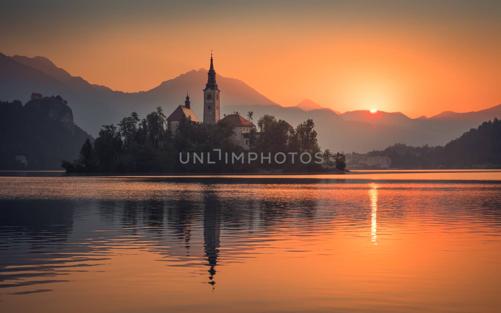 Little Island with Catholic Church in Bled Lake, Slovenia at Sunrise with Castle and Mountains in Background