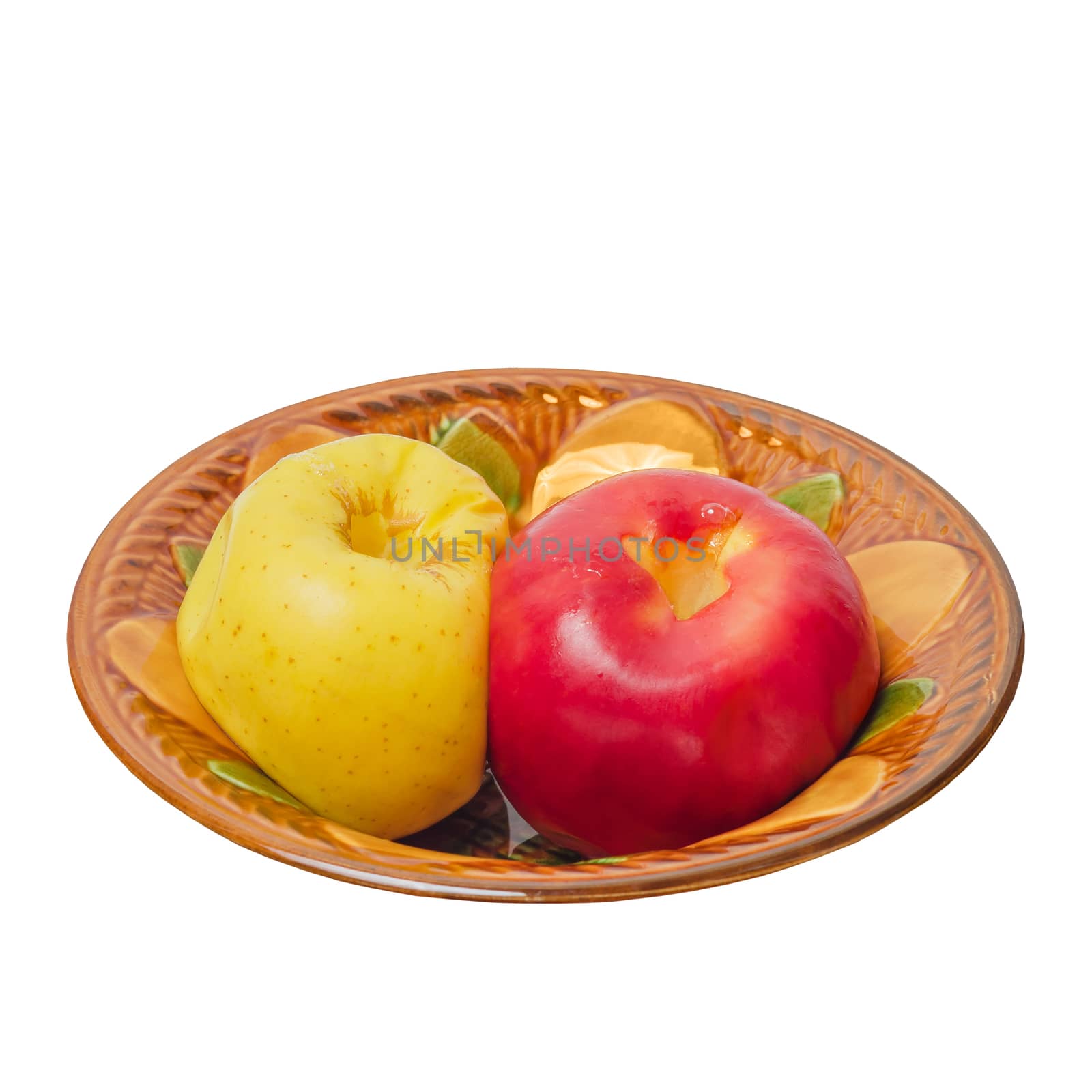 Two baked apples, red and yellow in a ceramic bowl. Isolated on a white background.