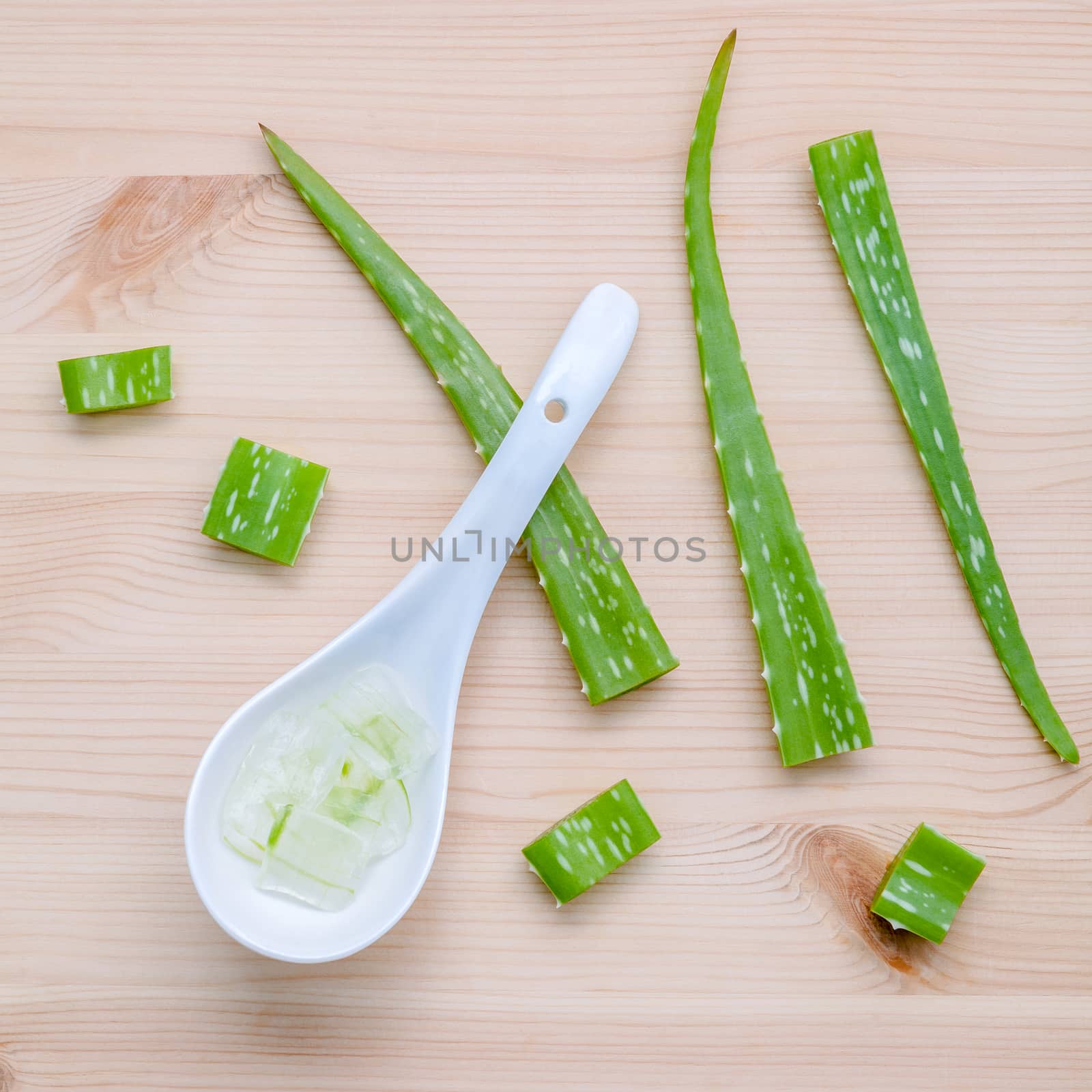 Alternative skin care  aloe vera gel in wooden spoons with aloe vera leaves set up on wooden table.