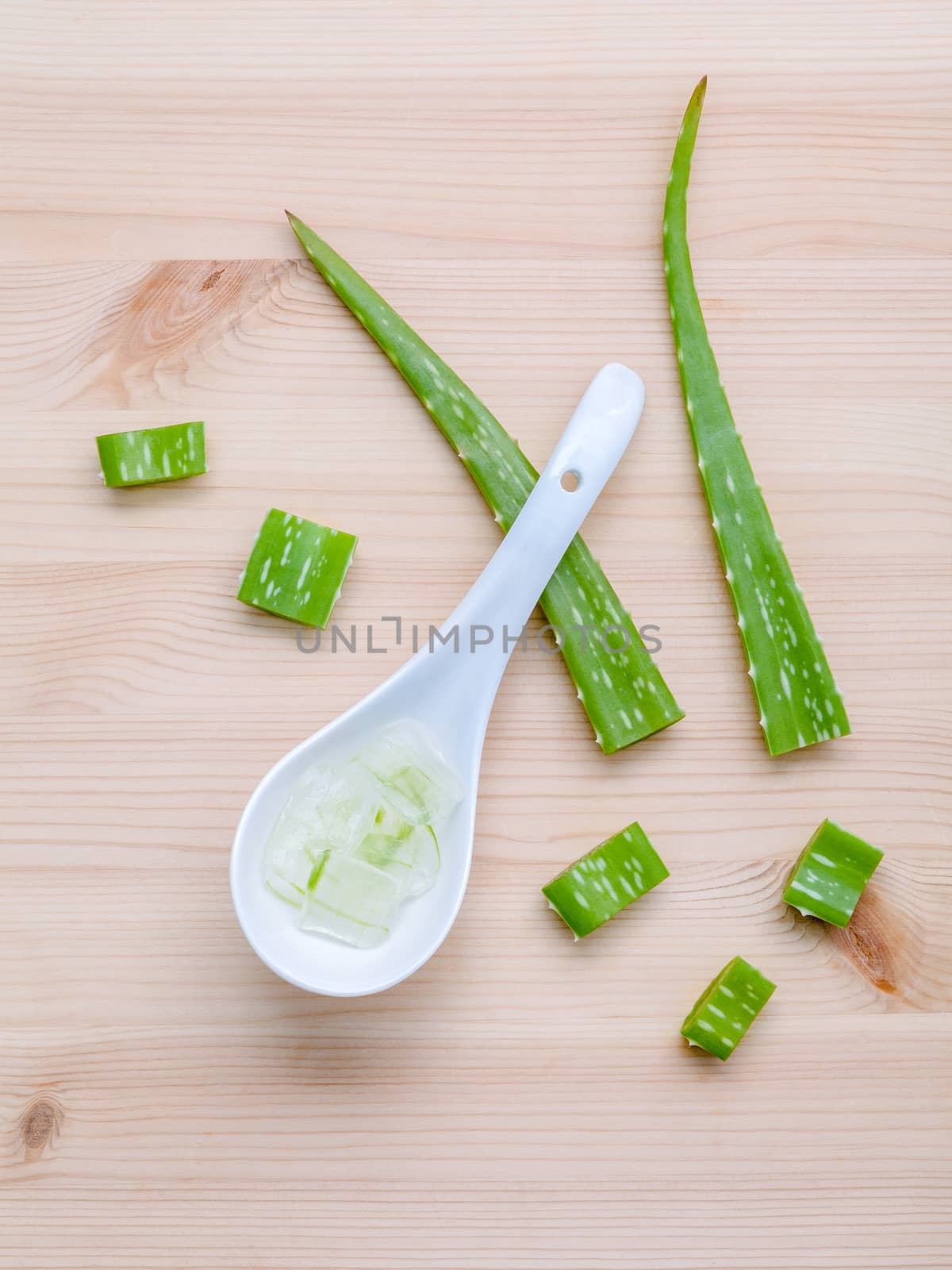 Alternative skin care  aloe vera gel in wooden spoons with aloe vera leaves set up on wooden table.