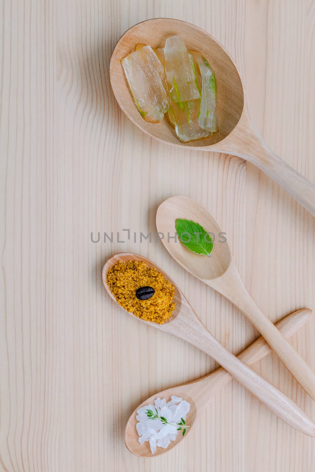 Alternative skin care and homemade scrubs aloe vera and sea salt in wooden spoons  set up on wooden table.