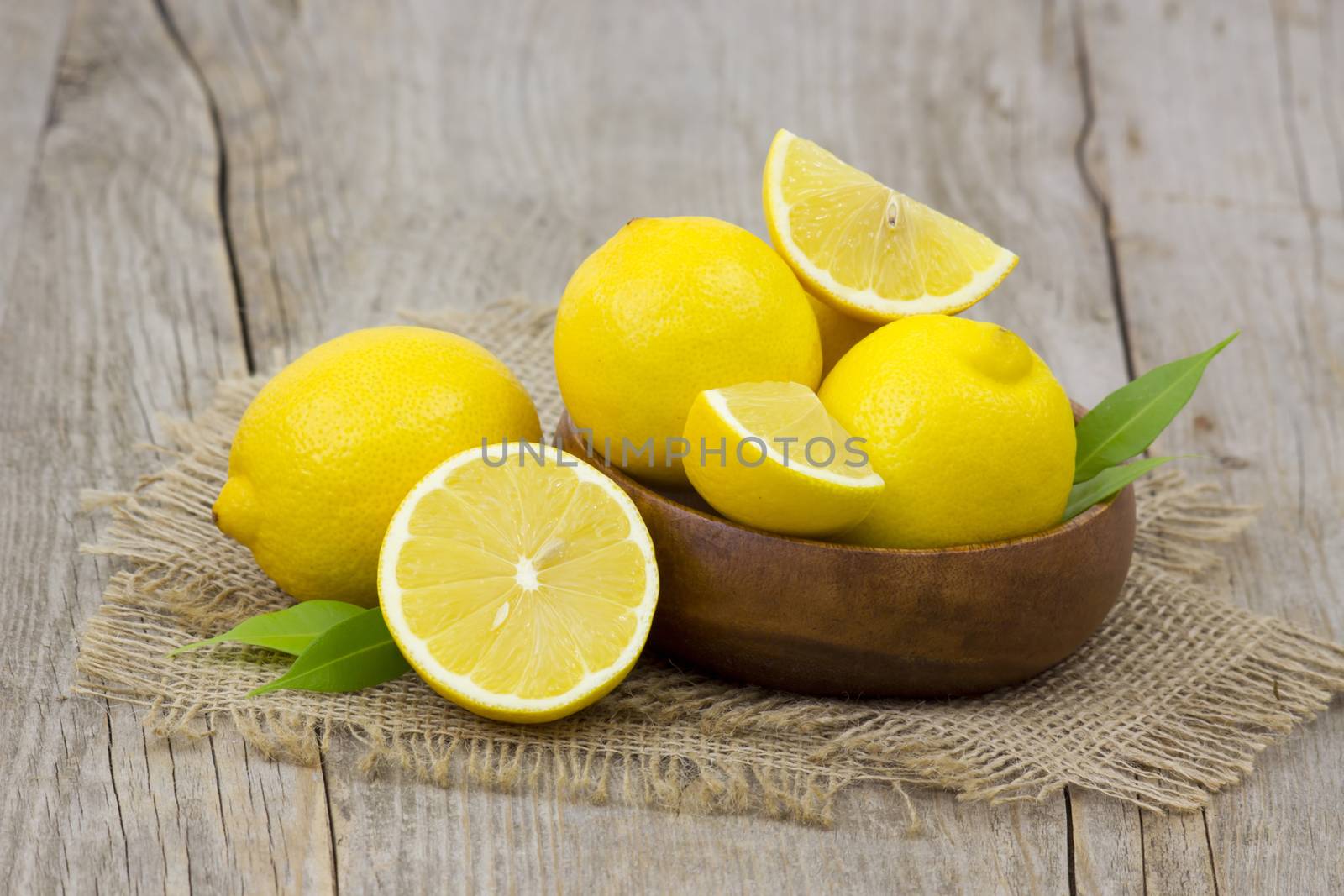 fresh lemons in a bowl on wooden background by miradrozdowski