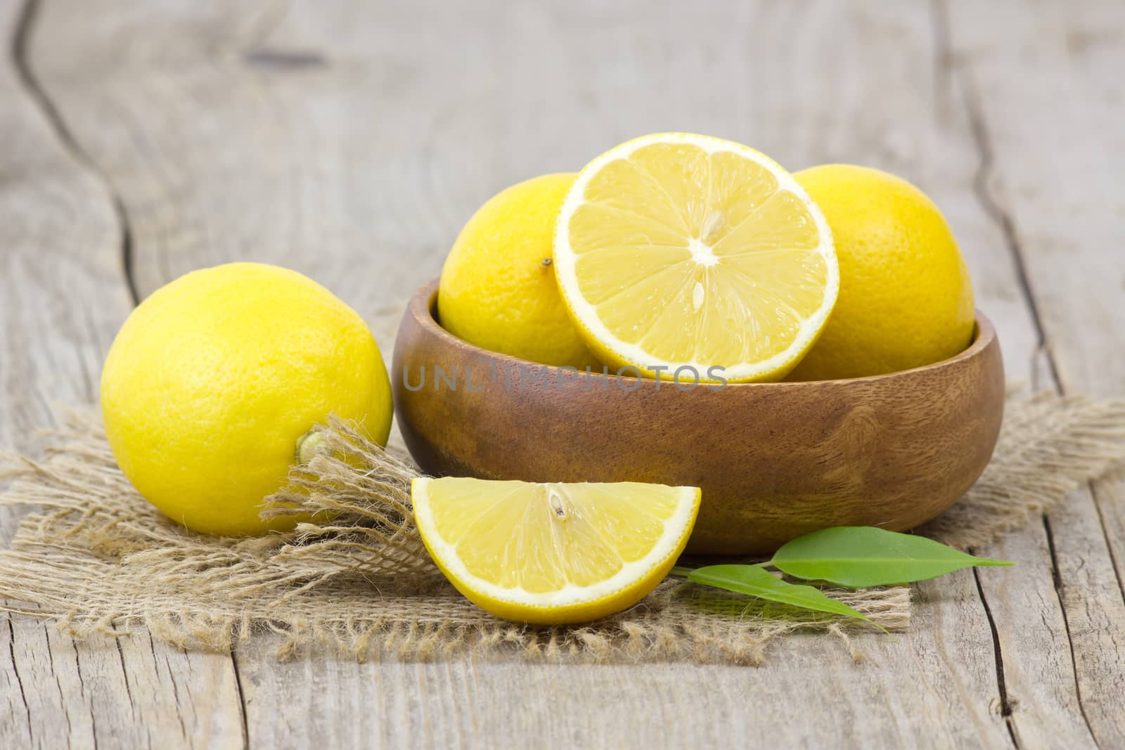 fresh lemons in a bowl on wooden background
