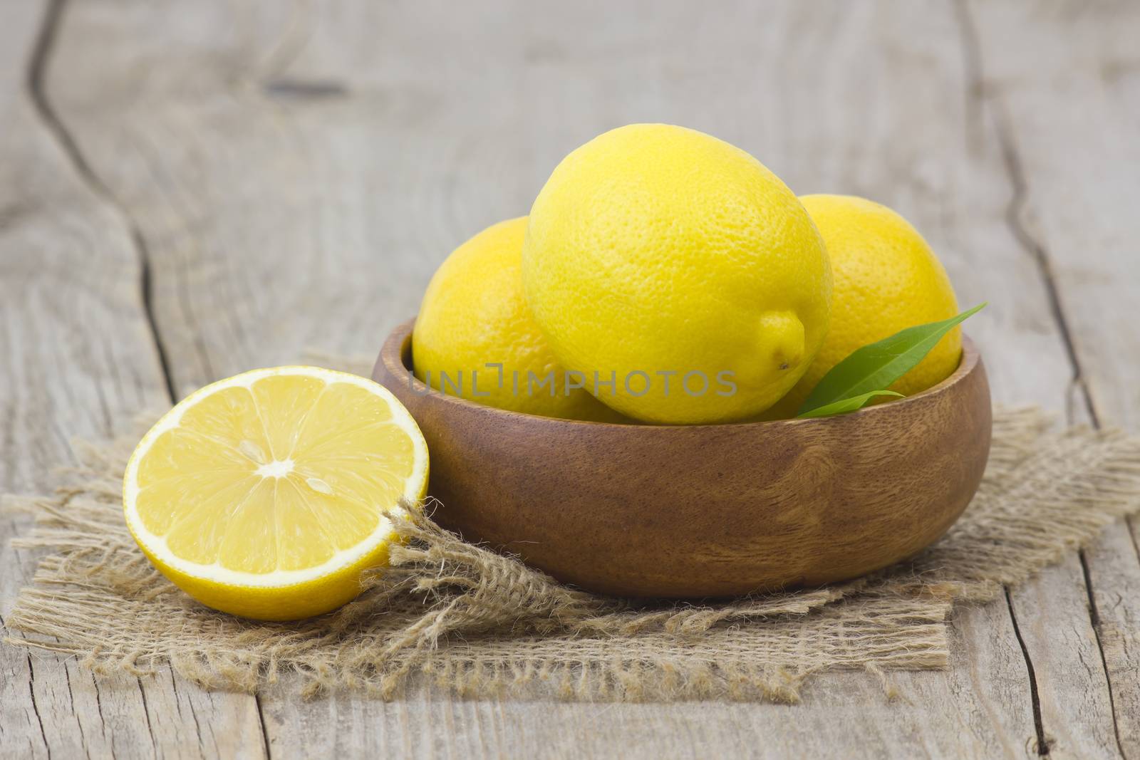 fresh lemons in a bowl on wooden background