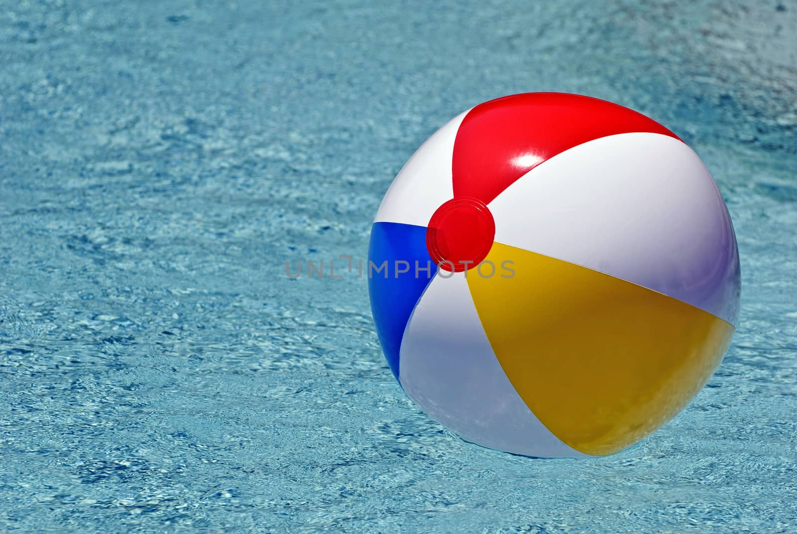 Colorful beach ball floating in swimming pool