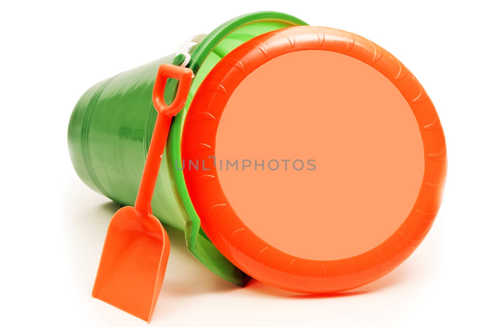 Horizontal shot of green toy pail with little shovel and frisbee.  Lots of copy space on frisbee.