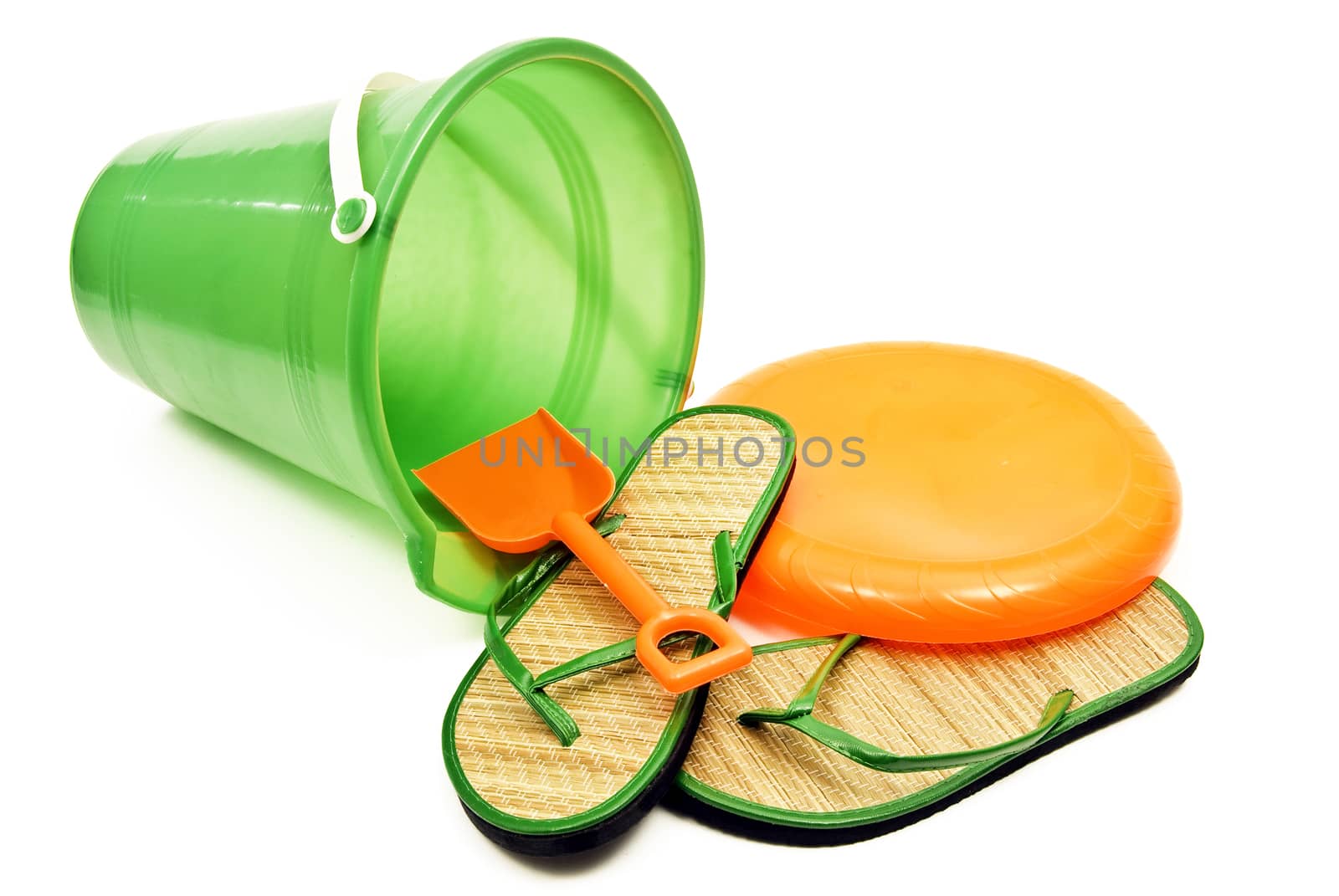 Horizontal shot of beach pail with shovel, flip flop sandals, and frisbee