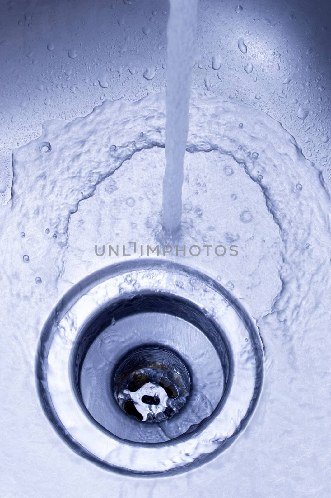 Vertical shot of a stainless steel sink with water running down into drain.