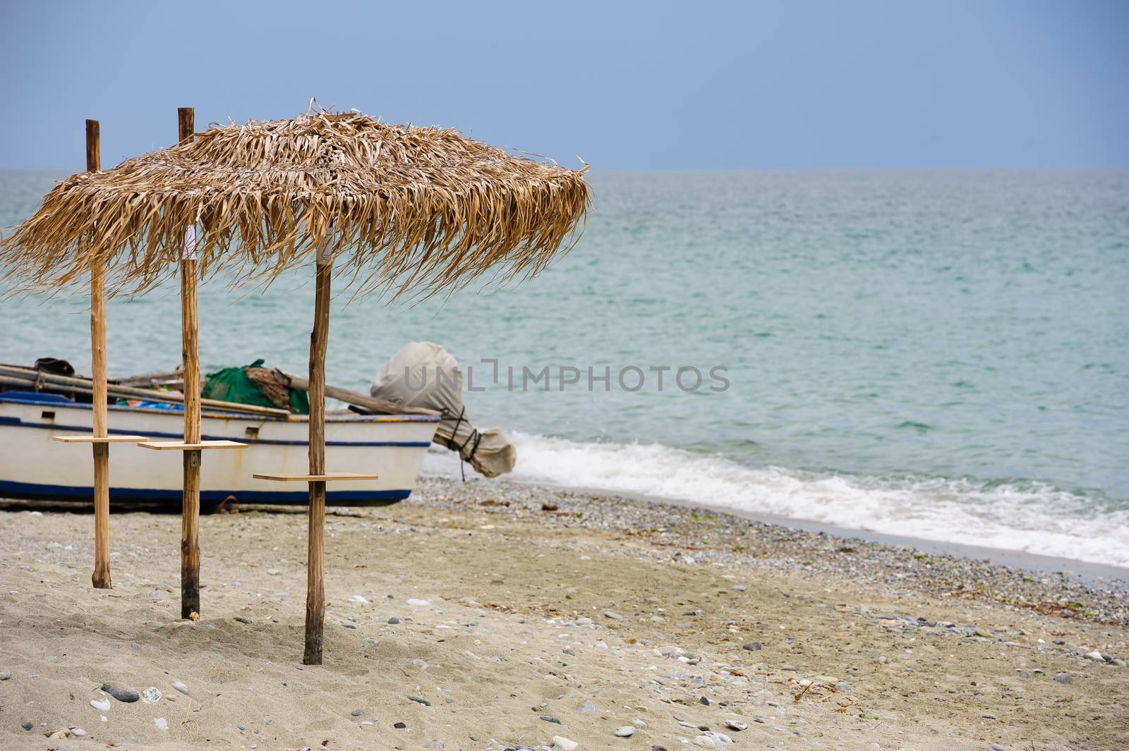 cane umbrellas and fishers boats at the beach