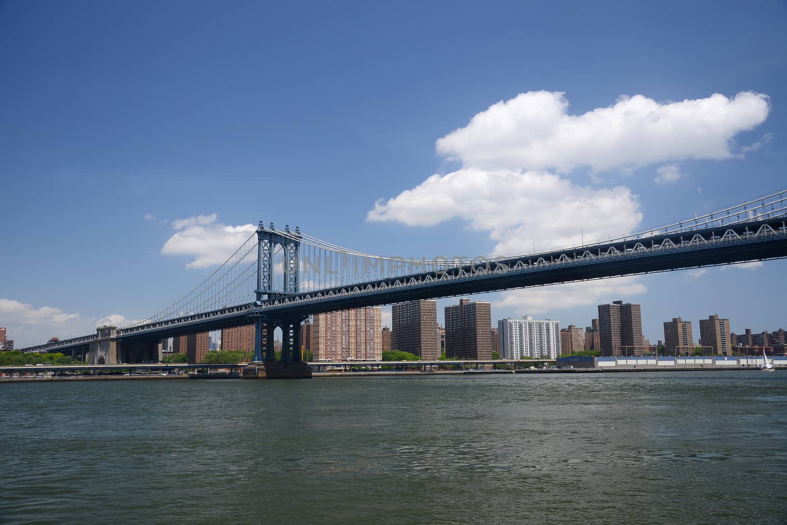 brooklyn bridge under a blue sky with downtown new york city as a background