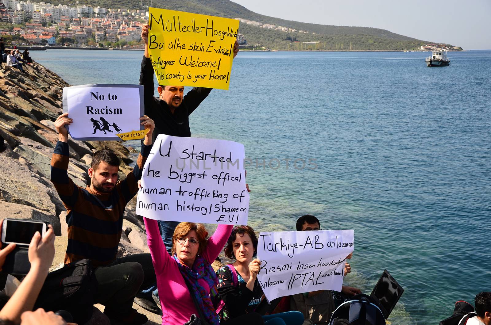 TURKEY, Dikili: A woman holds a sign reading EU started the biggest official human trafficking of human history. Shame on EU! as migrants who are deported from Lesbos and Chios islands in Greece to Turkey, arrive on April 4, 2016 in the port of Dikili, in Izmir district. Migrants return from Greece to Turkey begun under the terms of an EU deal that has worried aid groups, as Athens struggles to manage the overload of desperate people on its soil. Over 51,000 refugees and migrants seeking to reach northern Europe are stuck in Greece, after Balkan states sealed their borders. Hundreds more continue to land on the Greek islands every day despite the EU deal.
