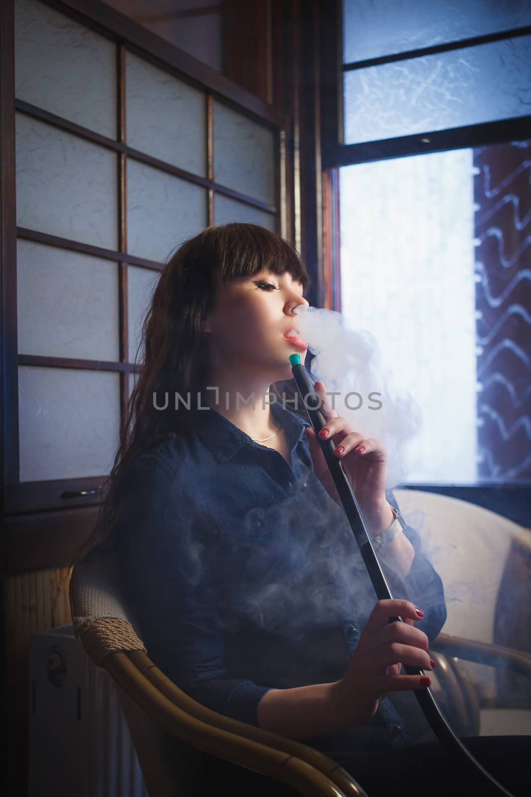 Concept: leisure lifestyle. Beautiful young woman with hookah in a bar restaurant