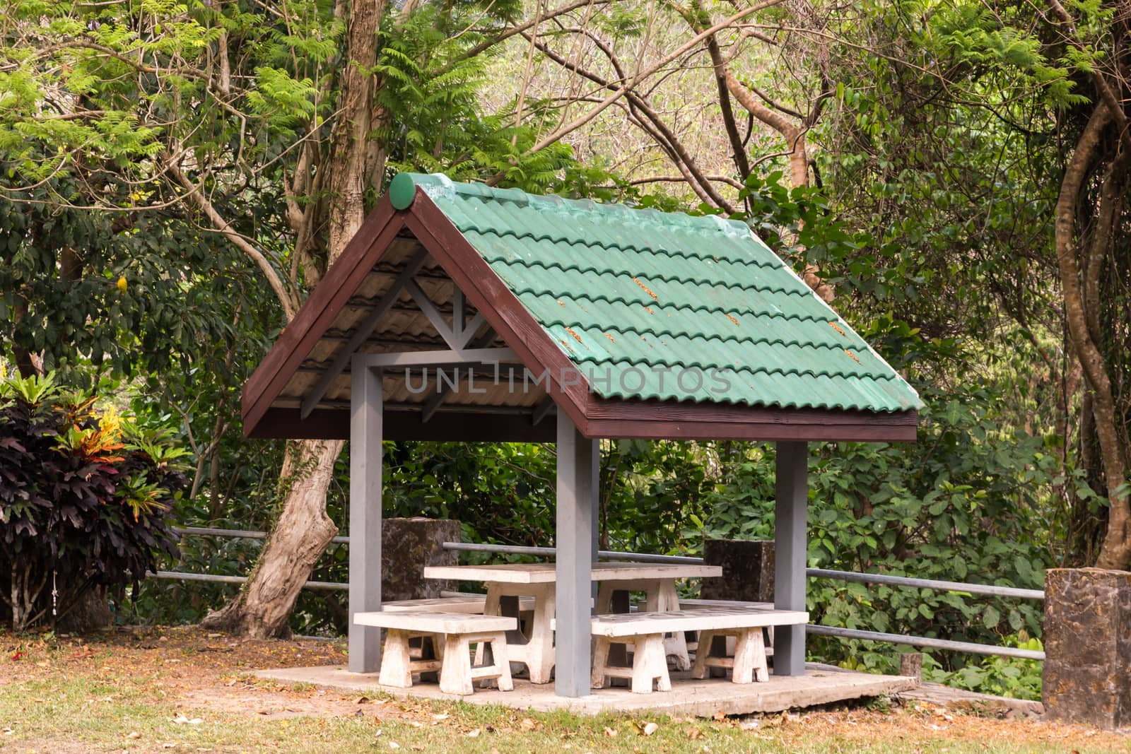 wooden gazebo with a green roof in the park