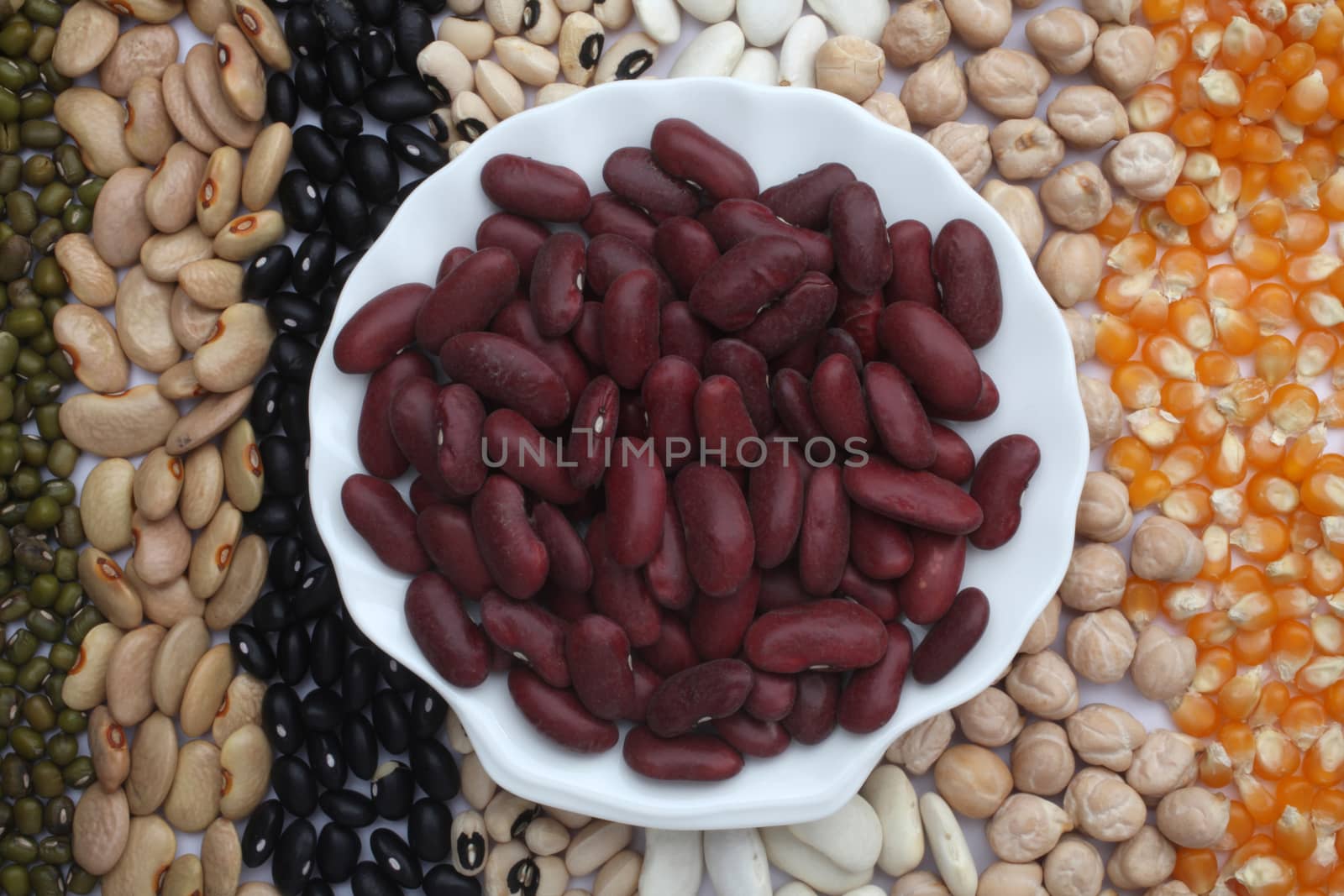Ceramic plate with red beans over seeds and grains background