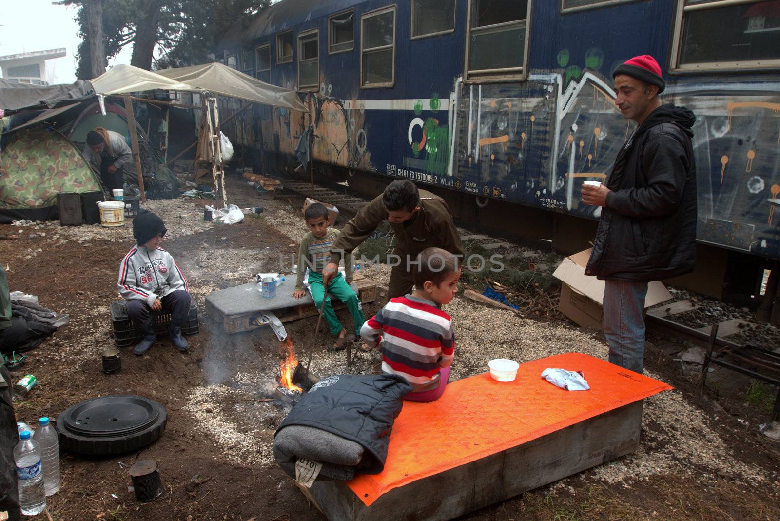 GREECE, Idomeni: Children warm up next to a fire at a makeshift camp on April 4, 2016 at Greece-Macedonian border, near Idomeni village where thousands of people are stranded by the Balkan border blockade. Migrants return from Greece to Turkey begun under the terms of an EU deal that has worried aid groups that same day, as Athens struggles to manage the overload of desperate people on its soil. Over 51,000 refugees and migrants seeking to reach northern Europe are stuck in Greece, after Balkan states sealed their borders. Under the agreement, designed to halt the main influx which comes from Turkey, all irregular migrants arriving since March 20 face being sent back, although the deal calls for each case to be examined individually. For every Syrian refugee returned, another Syrian refugee will be resettled from Turkey to the EU, with numbers capped at 72,000.