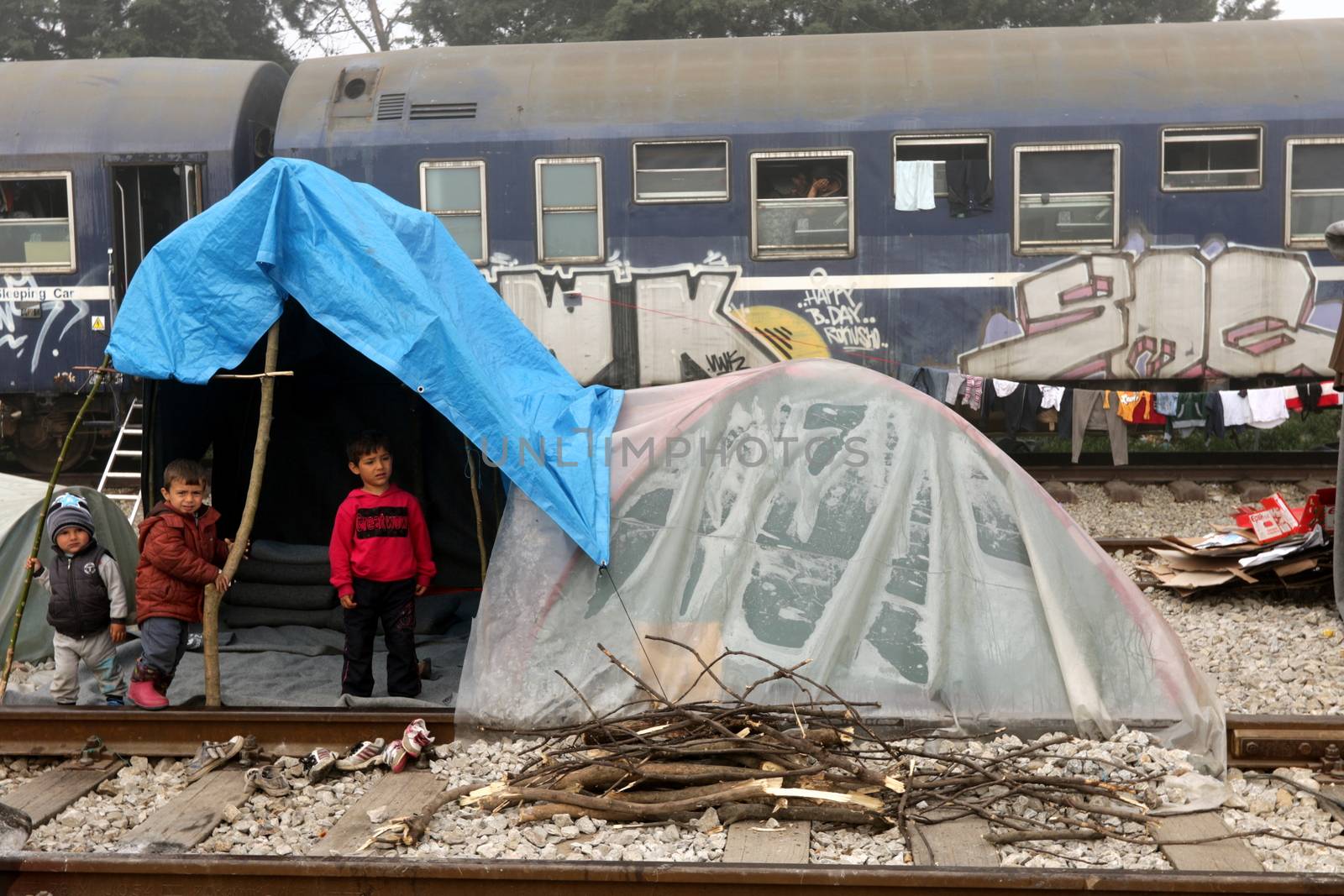 GREECE, Idomeni: Children stand next to a railway line in a makeshift camp on April 4, 2016 at Greece-Macedonian border, near Idomeni village where thousands of people are stranded by the Balkan border blockade. Migrants return from Greece to Turkey begun under the terms of an EU deal that has worried aid groups that same day, as Athens struggles to manage the overload of desperate people on its soil. Over 51,000 refugees and migrants seeking to reach northern Europe are stuck in Greece, after Balkan states sealed their borders. Under the agreement, designed to halt the main influx which comes from Turkey, all irregular migrants arriving since March 20 face being sent back, although the deal calls for each case to be examined individually. For every Syrian refugee returned, another Syrian refugee will be resettled from Turkey to the EU, with numbers capped at 72,000.