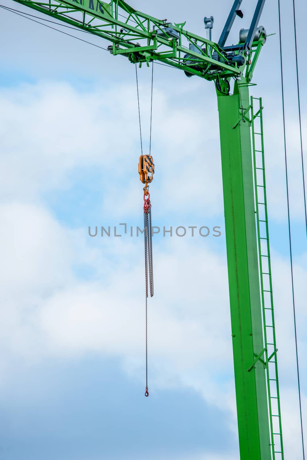 Green crane with a chain in cloudy weather
