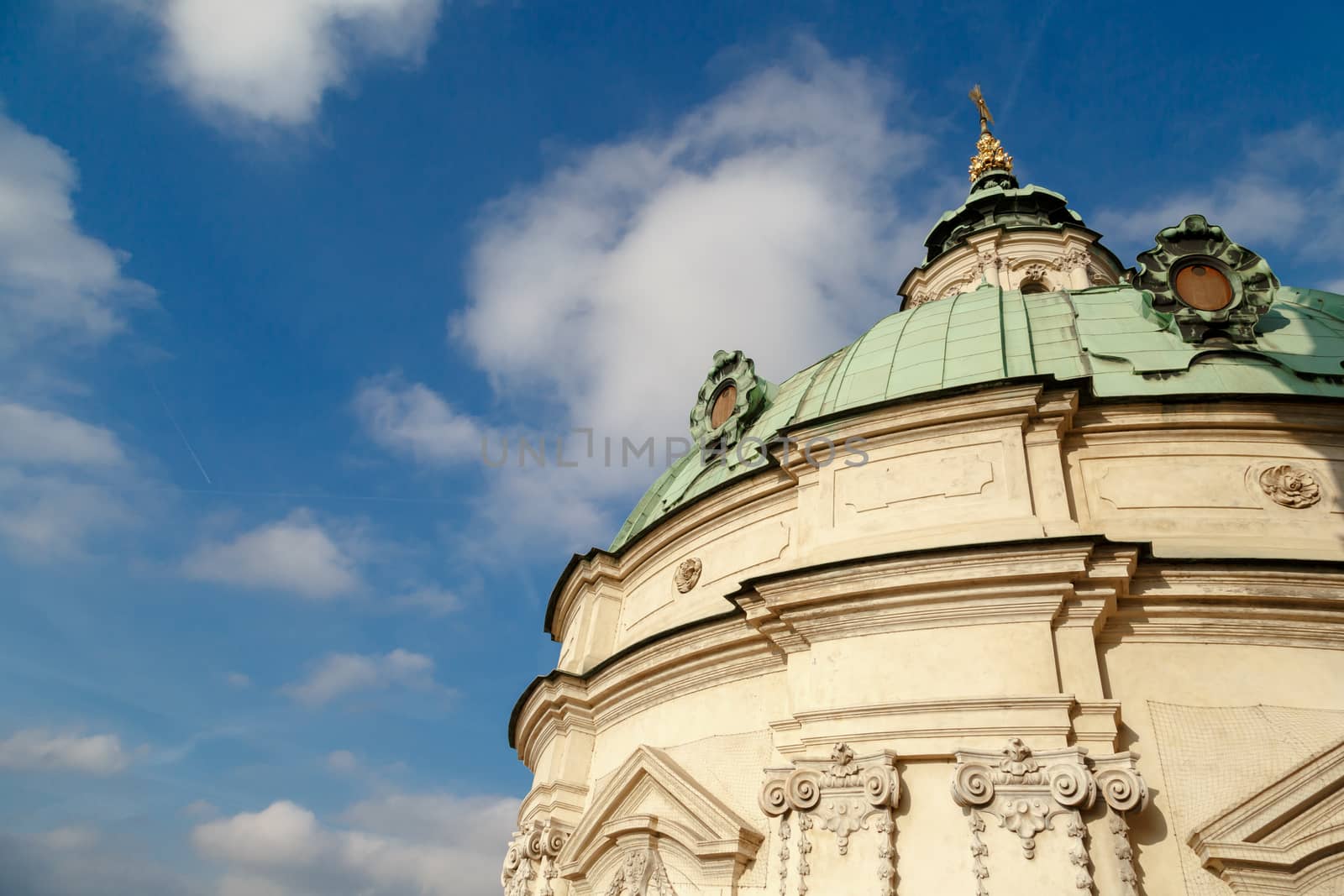 Close up detailed dome view of historical St Nicholas Church in Prague, on cloudy blue sky background.