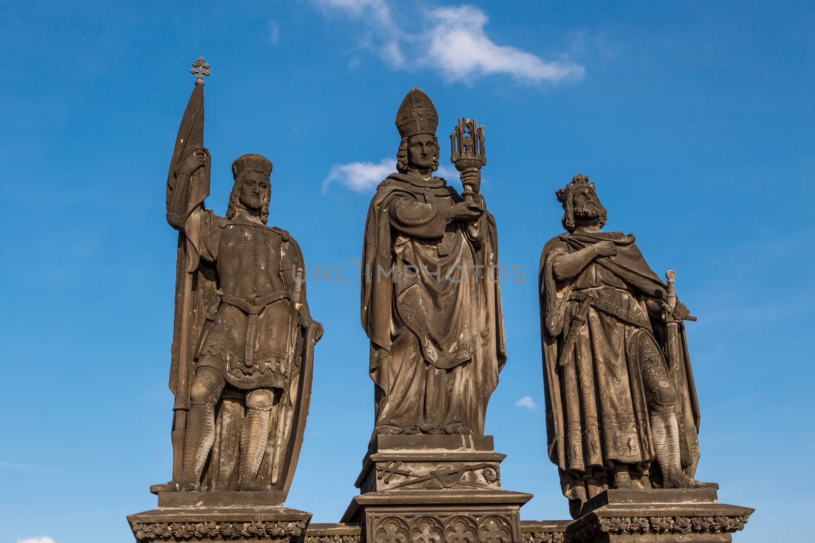 Close up detailed view of historical gothic granit sculptures on Charles Bridge in Prague, on bright blue sky background.