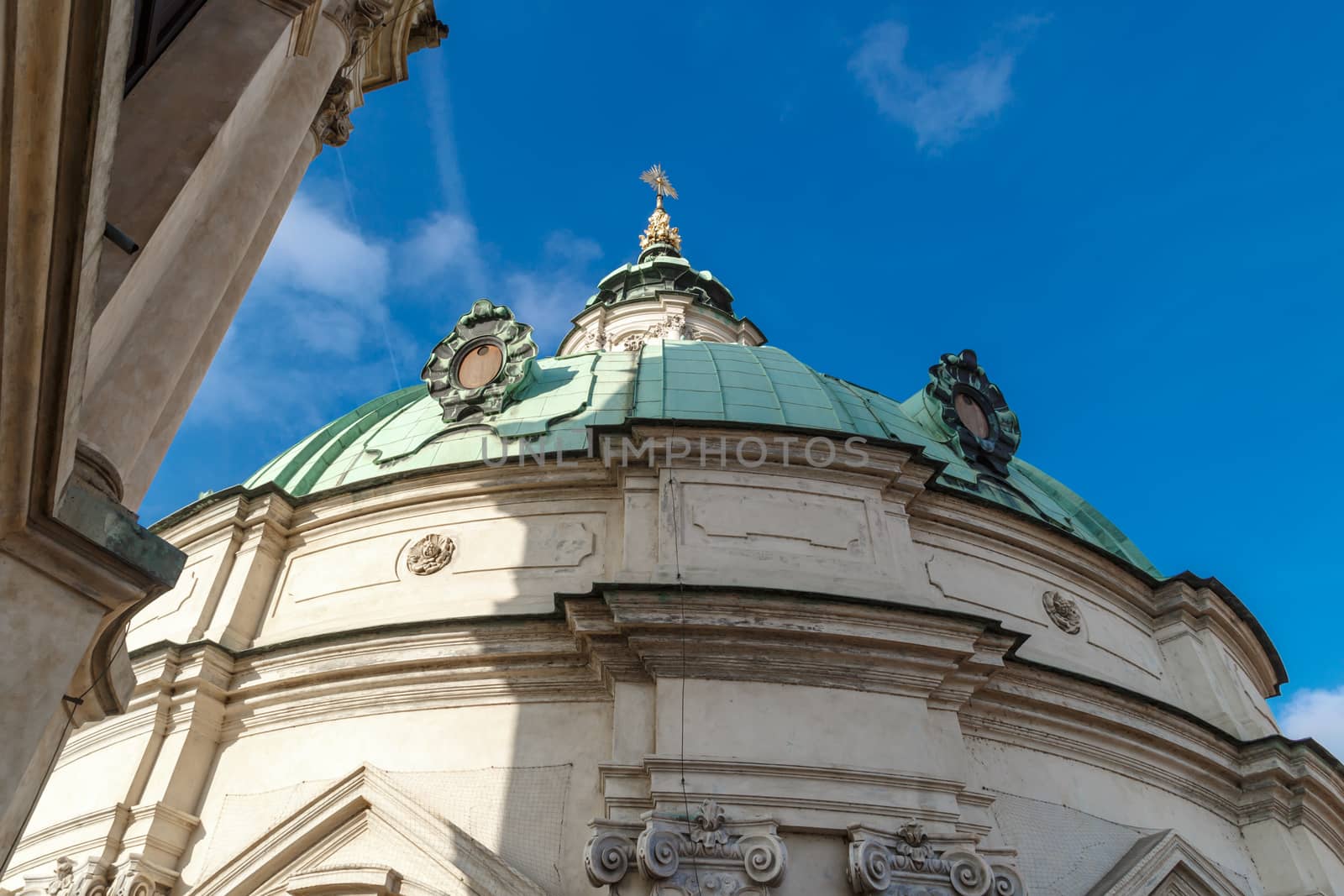 Close up detailed dome view of historical St Nicholas Church in Prague, on cloudy blue sky background.