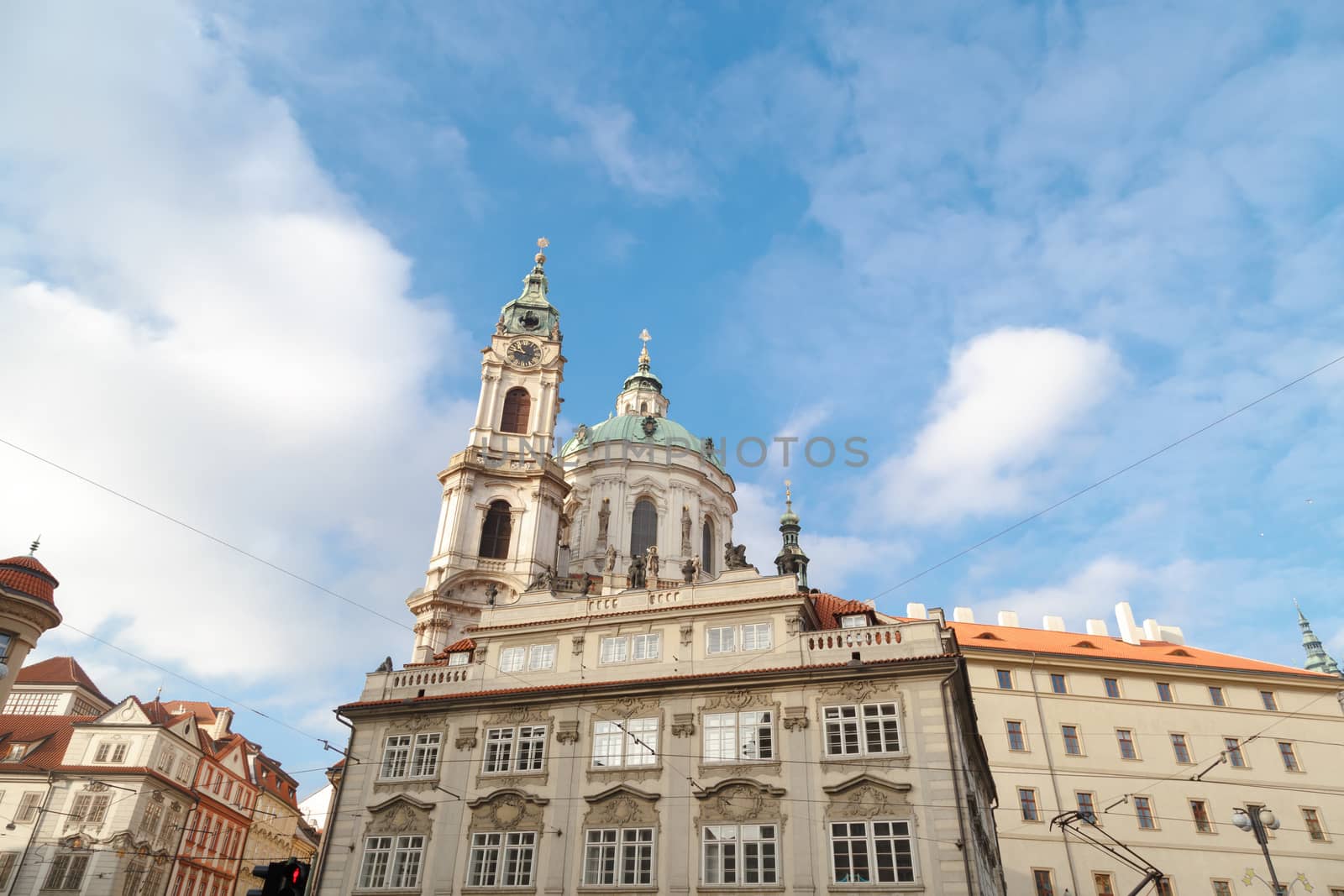 Close up detailed dome view of historical St Nicholas Church in Prague, on cloudy blue sky background.