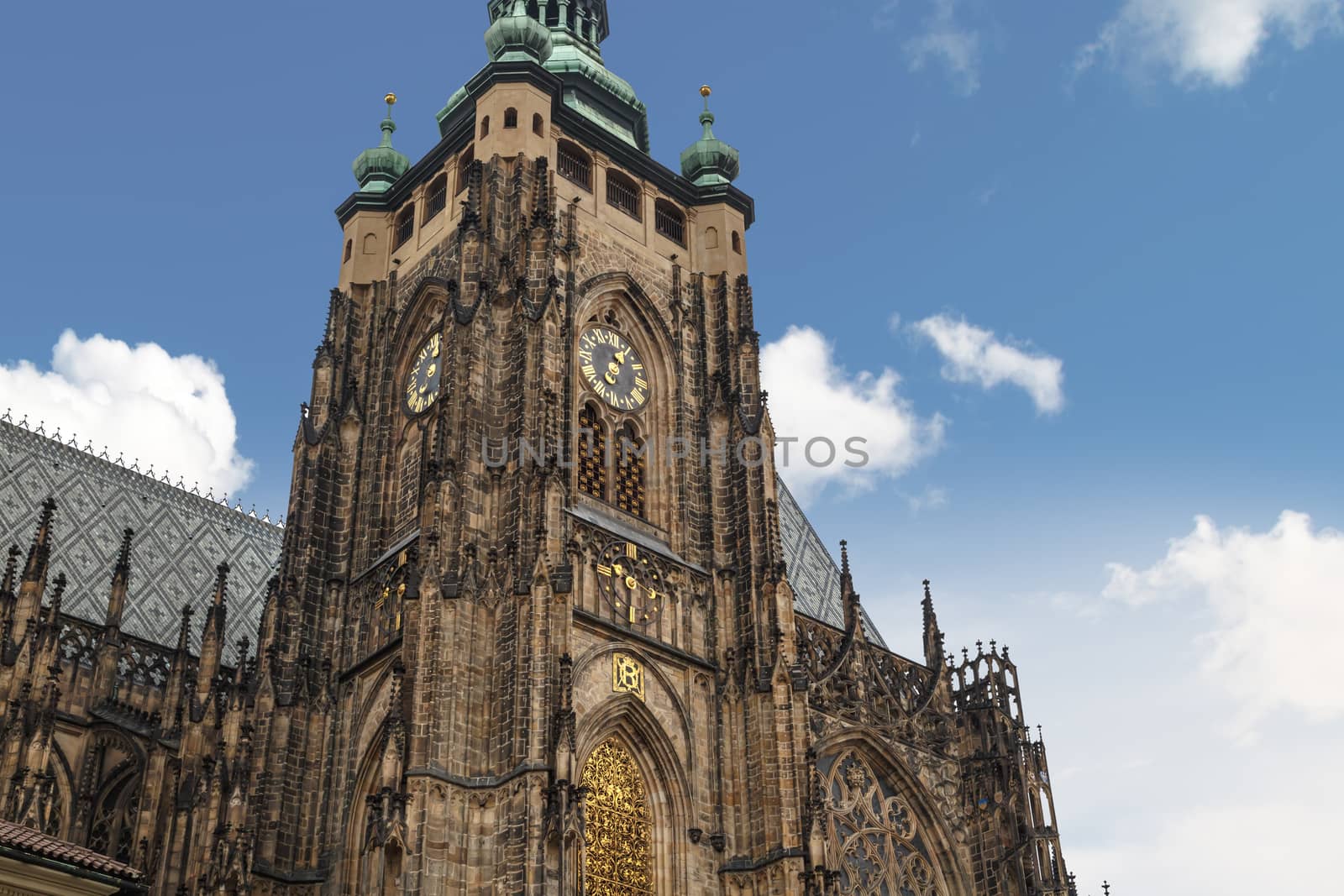 Bottom view of historical gothic St. Vitus Cathedral in old town of Prague, found in 1344, on cloudy blue sky background.