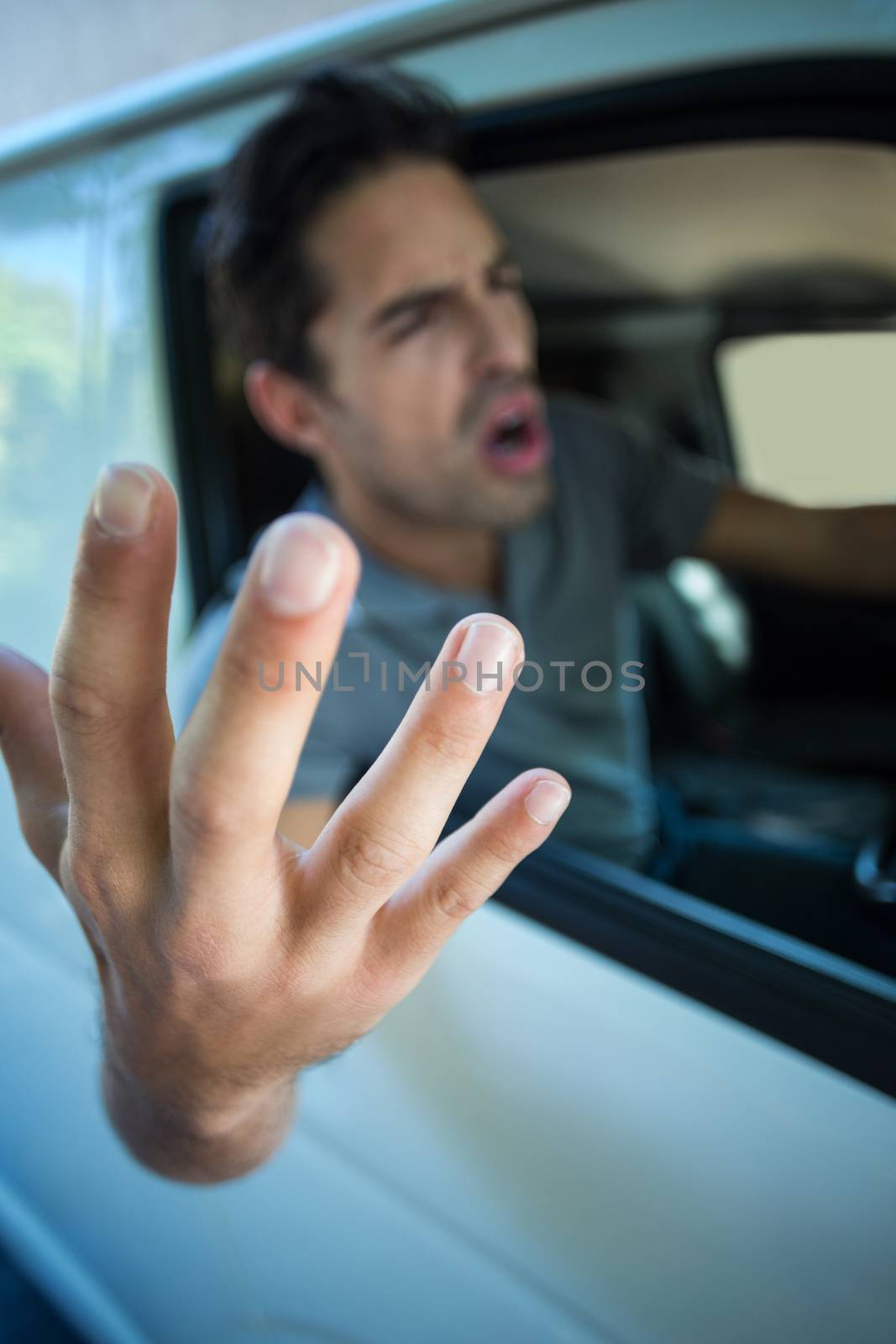 Angry young man gesturing while sitting in car